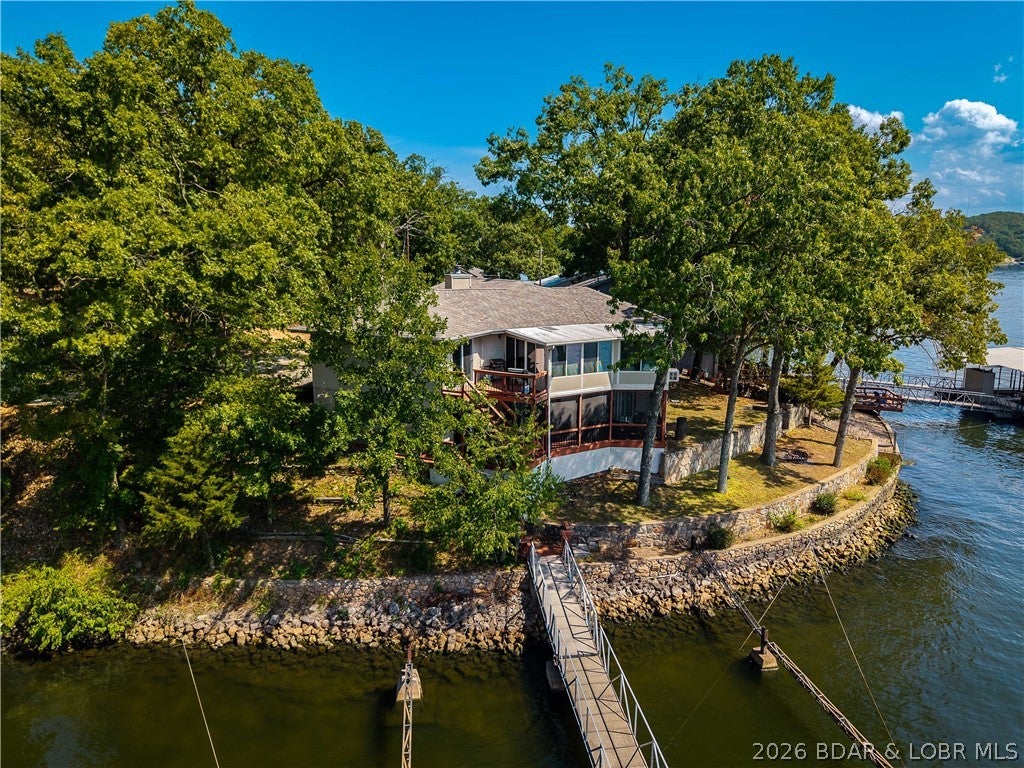 130 FEET OF LAKEFRONT, COVE-PROTECTED DOCK & ROOM FOR EVERYONE—this is the lake home you've been waiting for! This beautifully updated 4-bedroom home features 3 private ensuites, an updated kitchen and baths throughout. The kitchen offers granite countertops, stainless steel appliances and a double oven. The primary suite features double sinks, a walk-in shower and heated floors. Just off the kitchen and main-level living area, the heated and cooled sunroom is the perfect place to relax—open the windows and let the lake breeze roll in. Downstairs offers even more space with a fireplace, bar, laundry room and screened-in porch. Outside, enjoy 130 ft. of lakefront and a concrete dock with cove protection, away from the main channel. Includes 12x32 and 10x24 slips, a 10,000 lb. boat lift and 2 PWC lifts. Reverse osmosis system, 1-car garage, plus the septic was serviced and pumped in early summer 2026.