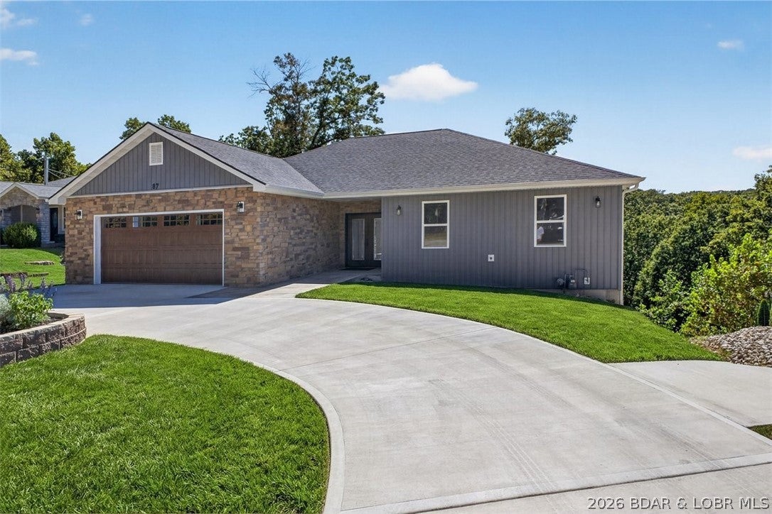 NEW CONSTRUCTION in a fantastic central Lake Ozark location! From the moment you arrive, stone exterior accents, a circle driveway and impressive glass front doors with a covered entry set the tone for this beautifully finished home. Inside, vaulted ceilings, luxury vinyl plank flooring and high-end lighting create a bright, modern feel throughout. The kitchen features quartz countertops, marble backsplash and top-of-the-line stainless appliances, opening to a spacious main living area perfect for entertaining. A huge laundry room offers a full sink and abundant counter space with plenty of room to double as a walk-in pantry. The master suite features a custom closet system and large tiled walk-in shower. Downstairs you'll find a second oversized living area, wet bar and a second master suite, providing excellent space for guests or extended family. Car lovers will appreciate the oversized 2-car garage with epoxy floors, plus a separate lower-level garage ideal for a UTV, golf cart, workshop or ultimate man cave. Quality finishes, flexible living spaces and a convenient location close to everything Lake Ozark has to offer.  Check it out TODAY!