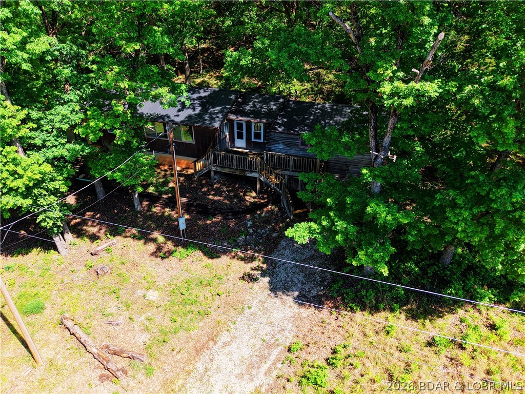 Trade the subdivision for the sound of silence at this 11± acre wooded "basecamp" in Stover. The heart of the home is a true stacked-log cabin—providing a rugged, authentic Ozark character you simply cannot recreate—now expanded into a functional 1,300+ sq ft, 2-bed, 1-bath residence. Best of all? You can work from the woods with high-speed internet available.

Surrounded by heavy timber on three sides, this property is a outdoorsman's  dream. The detached 2-car garage is ready for ATVs and lake toys, while the terrain features a natural backstop area perfect for a private shooting range or target practice. With frequent deer and turkey sightings, you can hunt or wildlife-watch directly from your covered concrete patio.

Enjoy unmatched seclusion just minutes from the marina and lakefront amenities. Equipped with a new metal roof (2025), this property is built for the buyer who wants a tactical weekend getaway or a primary residence with zero neighbors in sight. Bring your tools and a little sweat equity to finish out this standout Ozark classic.