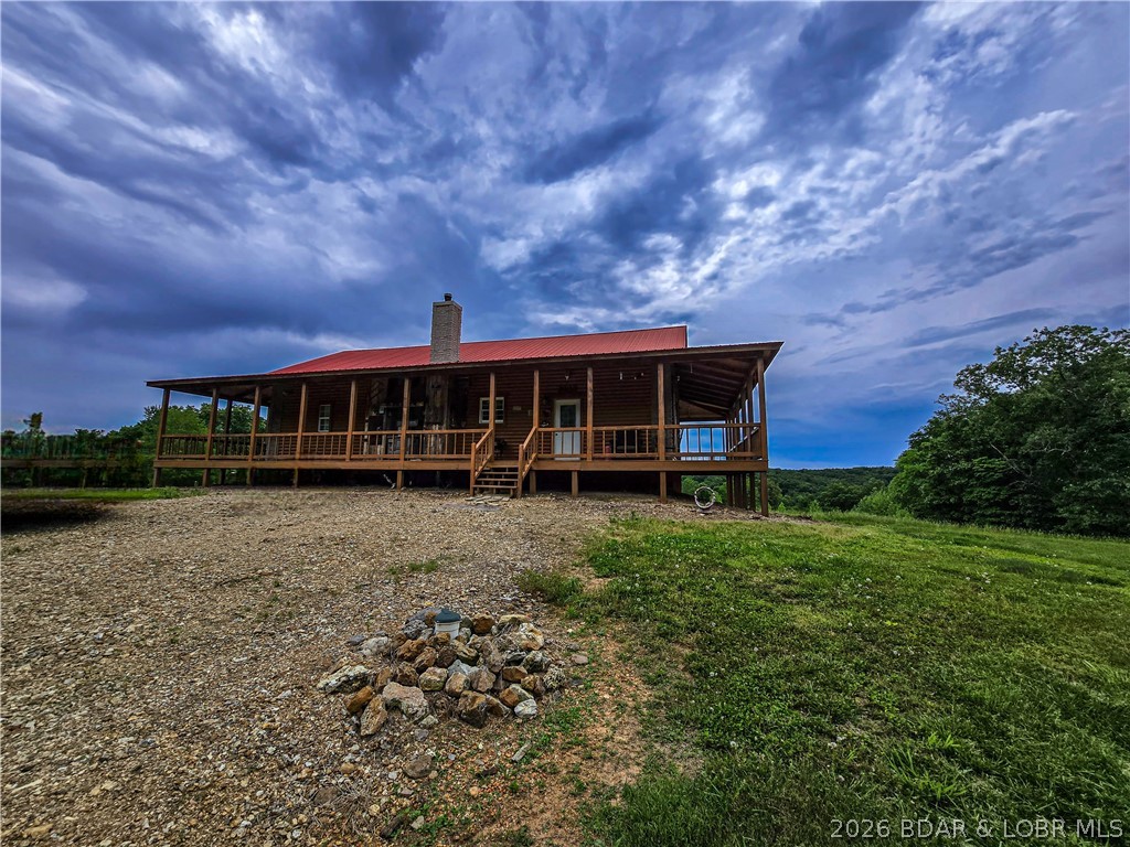 Travel beneath the wooden archway and feel the pace of life slow down. Set on over 90 acres of beautiful Missouri countryside, this charming log home offers the privacy, space, and peaceful setting so many are searching for. Inside, exposed beams, natural light, and a cozy fireplace create the perfect blend of rustic character and comfort. The main level features a primary bedroom with private bath and walk-in closet, plus a custom kitchen with double oven, generous counter space, breakfast bar, and plenty of cabinet storage. Upstairs, the loft makes a great kids’ space, playroom, or extra sleeping area. The finished basement offers a large bonus room ideal for family gatherings, hobbies, or additional bedroom space. Outside, enjoy morning coffee or evening sunsets from the wraparound deck. The barn/shop provides room for equipment, animals, storage, or projects. With abundant wildlife, hunting opportunities, and room for family and four-legged friends, this is your chance to relax and live in the peace and quiet of the country. Would be a great hunting resort as well or bring your own ideas.