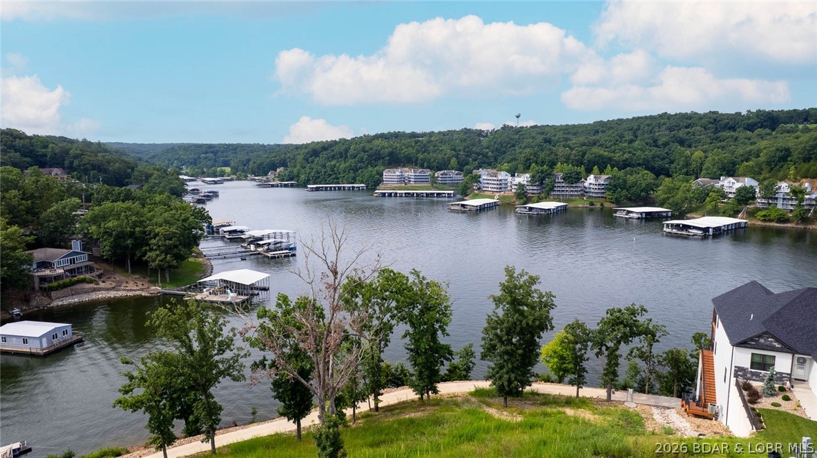 Prime Lake View Villa at The Villas at Tuscany! This barely used 4-bedroom, 3-bath, 2,930 sq. ft. villa offers the best view in the complex overlooking Libby Cove at the 1MM of Big Niangua. Built in 2022 this home features main-level living, two master suites, granite countertops, stainless steel appliances, and hardwood floors. Enjoy outdoor living on large, covered screened decks on both levels while soaking in the lake views. The spacious primary suite boasts a custom walk-in closet and oversized tiled shower. An oversized 2-car garage provides plenty of room for lake toys. With a gentle driveway and a gated community this helps with ease. Community amenities include pool, pickleball, fire pit & pavilion, plus golf cart access with no steps to the dock. A 14x40 slip (A-8) with dock box in the list price, while a 16x44 slip (A-12) with a 8ft concrete fill and wet steps is available for additional purchase. Whether full-time or part-time, this no-maintenance setting offers the perfect balance of luxury, comfort, and lake living—just minutes from the iconic Four Corners! Sellers barely used as a summer getaway.