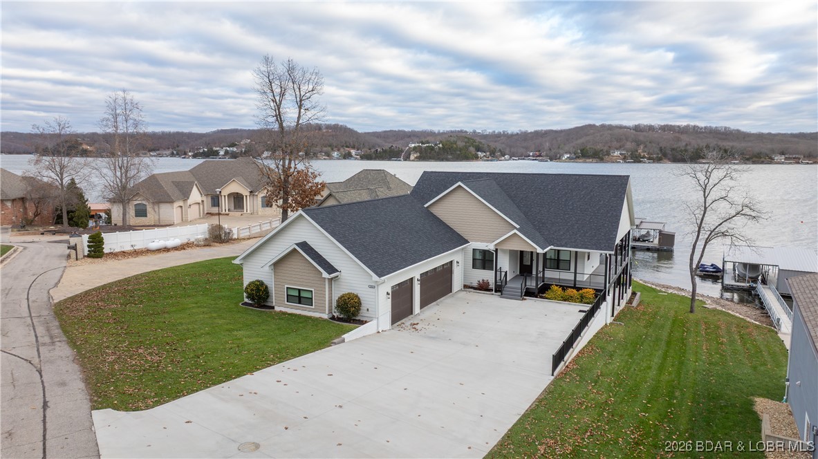 This gorgeous lakefront home truly has it all. Newly built in 2023, this 3,368-square-foot showstopper offers 5 spacious bedrooms and 3.5 bathrooms, perfectly designed for comfort, entertaining & lake living. Set in a quiet, upper-end neighborhood at the coveted 42 mile marker, the home captures huge, sweeping lake views & boasts an impressive 113 feet of pristine lakefront. 
Quality craftsmanship shines throughout, with Diamond Kote smart siding, composite decking, aluminum railings & a concrete driveway. Plus, a wrap around covered concrete patio—all combining for a very low-maintenance lifestyle. The flat, beautifully landscaped yard features a rip rap seawall & an exceptionally easy walk to the water, with only a couple of stairs off lower patio to the dock. Enjoy a concrete three-well dock complete with a swim platform & an 8x10 storage area, making lake days effortless & fun. A three-car garage, quality custom construction, and thoughtful design details round out this exceptional property. From the peaceful setting to the stunning views, this lakefront retreat checks every box and then some.  5th Bedroom is current workshop but could be convert with an en suite bathroom.