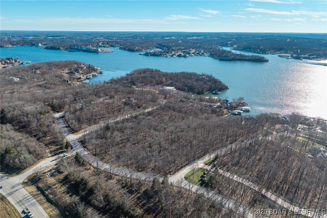 Surrounded by mature trees and natural Ozarks beauty, this wooded lot at The Villages at Shawnee Bend offers a peaceful, private setting within one of Lake of the Ozarks’ most distinguished communities. From the moment you arrive through the grand waterfall entrance, the neighborhood’s upscale character is clear. Residents enjoy access to a beautifully appointed clubhouse, resort-style community pool, championship tennis courts, and pickleball facilities, along with parks, and playgrounds. Paved roads and underground utilities make building seamless while preserving the natural landscape. Ideal for a custom home or lake retreat, this wooded homesite blends serenity, luxury, and an active lake lifestyle.