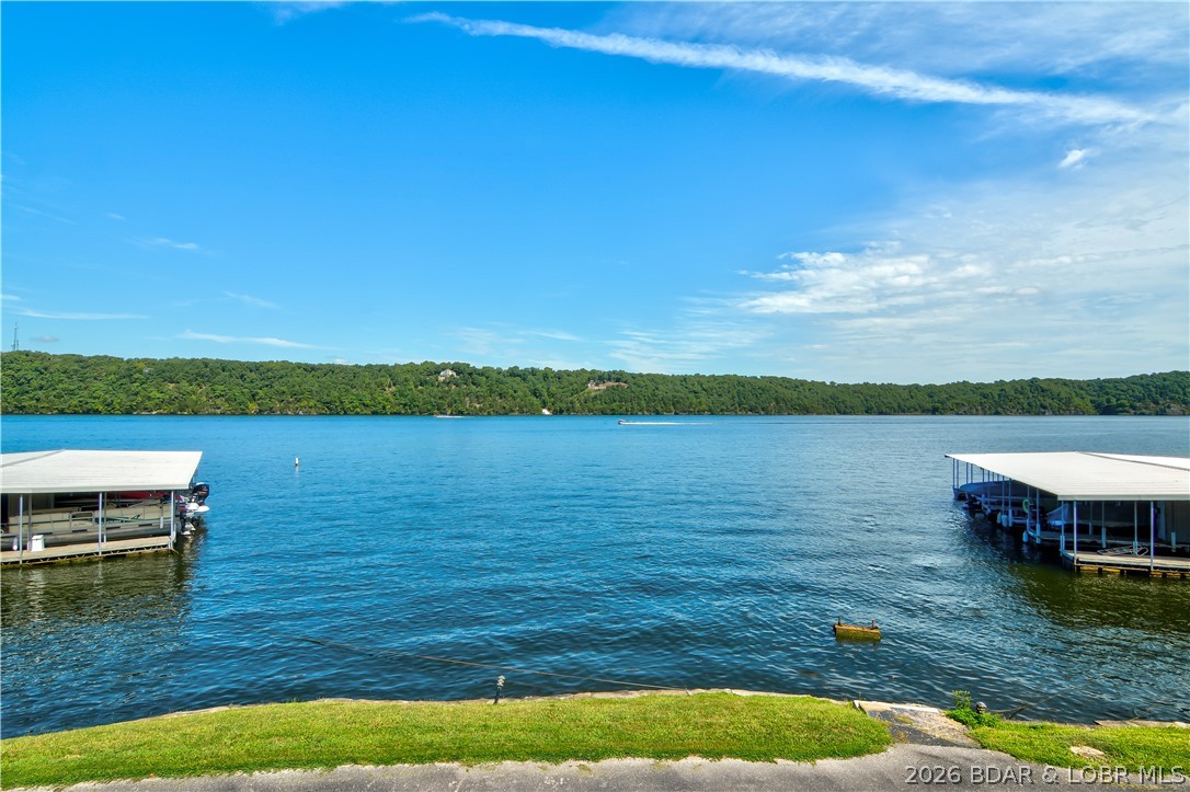 Space, comfort, and value come together in this furnished condo at Osage Heritage located at the 29 Mile Marker of Lake of the Ozarks. With easy parking just steps from the door, getting in & out is incredibly convenient. Inside you’ll find a spacious open floor plan that connects the living, kitchen, and dining areas—perfect for relaxing with family or entertaining guests. One of the standout features is the wraparound deck, offering an expansive outdoor living space with a big lake view from the main part of the deck.  It also includes a gate with direct access to the grassy area, making it easy to enjoy the outdoors.
The huge master suite features an attached bath with walk-in shower, while the generous guest bedroom sits conveniently across from the second full bathroom. The seller has recently installed new flooring & appliances giving the condo a fresh, updated feel that shows well. The unit includes a 12X32 boat slip in a new dock plus access to the community pool just a short walk away. Osage Heritage does not allow nightly rentals, creating a quieter, more relaxed atmosphere.  Property is under contract with a 24 hour kickout, please continue to show.