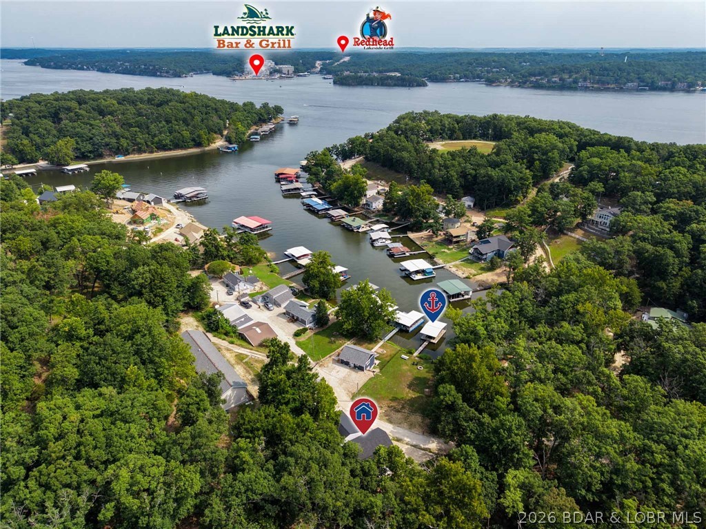 TURNKEY lakefront at the 26MM in Sunrise Beach - sold fully furnished and operating as an active nightly rental. SLEEPS 16 across 5 bedrooms and 4 baths, with multiple living areas and a finished full basement - built for large families or two families traveling together. Tucked in a quiet cove with a level, gentle-sloping lot, seawall, and an easy walk to your dock. Completely updated with luxury vinyl plank, tiled baths, walk-in showers, custom cabinets and walk-in closets. The converted garage is the ultimate game zone with ping pong, basketball and arcade games, and a DETACHED 2-CAR GARAGE with electric and workshop still leaves room for the boat and toys. Fire pit overlooking the water and a boat ramp next door. Minutes to Landshark, Redhead and the Lake's favorite waterfront bars by land or water. Two parcels included and HOA only $23/month. Full-time residence, vacation retreat, or proven income producer - ready to go on day one.