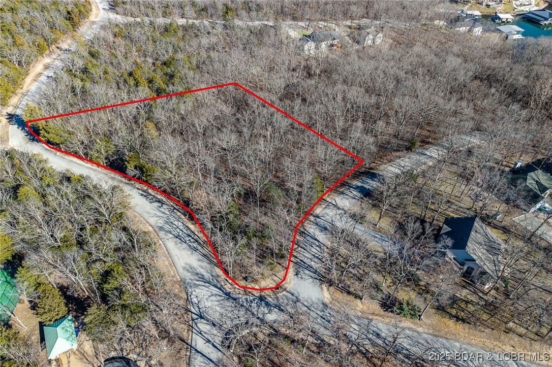 Surrounded by mature trees and natural Ozarks beauty, this wooded lot at The Villages at Shawnee Bend offers a peaceful, private setting within one of Lake of the Ozarks’ most distinguished communities. From the moment you arrive through the grand waterfall entrance, the neighborhood’s upscale character is clear. Residents enjoy access to a beautifully appointed clubhouse, resort-style community pool, championship tennis courts, and pickleball facilities, along with parks, and playgrounds. Paved roads and underground utilities make building seamless while preserving the natural landscape. Ideal for a custom home or lake retreat, this wooded homesite blends serenity, luxury, and an active lake lifestyle.