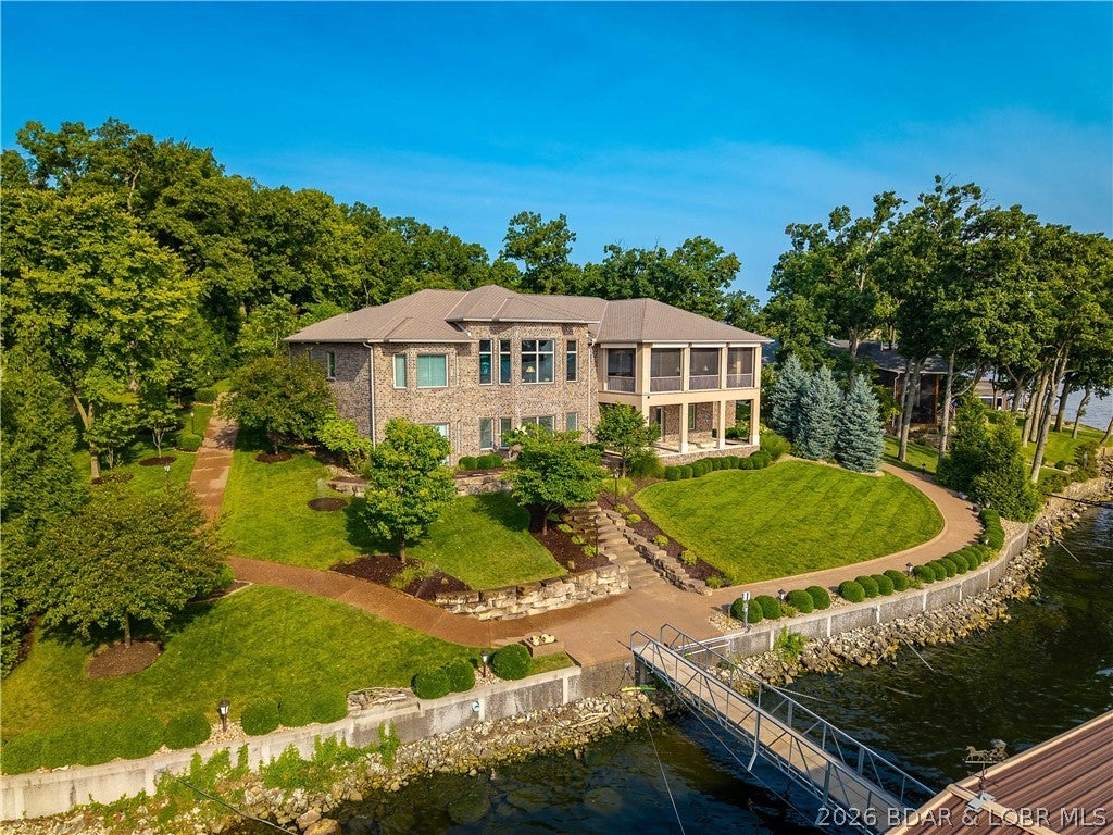 Welcome to this custom built estate, ideally located in coveted Six-Mile Cove with breathtaking main channel views & over 190 feet of shoreline. Designed for luxury living & effortless entertaining, this all-brick masterpiece showcases exceptional craftsmanship & timeless elegance. Main level features two suites, including an incredible primary retreat w/ a spa-inspired bath, separate his-and-her water closets, & a custom walk-in closet w/ private laundry. Soaring ceilings & a dramatic wall of windows showcase the spectacular lake views. Chef's kitchen features custom cabinetry, premium appliances. Screened lakeside deck is the ultimate outdoor living space, complete w/a gas fireplace & hurricane shutters for year-round enjoyment. Walkout lower level offers a family room,full custom bar, game area, 2 additional en-suites, a large bunkroom/fitness room & storage room. 4th garage. Additional features: elevator, central vac, oversized 3-car garage level driveway, gentle lot w/a golf cart path surrounding home, a large hot tub/spa with automatic cover. Wave break system protecting the concrete dock. Ample room to add a pool & the majority of the furnishings & electronics are included.