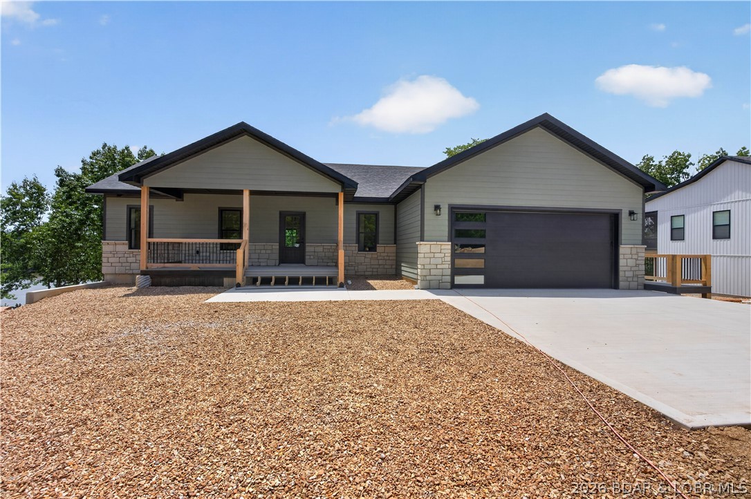 Stunning new-construction waterfront home at the Lake of the Ozarks! This spacious home features an open floor plan designed for entertaining, with breathtaking lake views from multiple levels. The main level offers a large living room with an electric fireplace, a spacious kitchen with abundant cabinet space and a walk-in pantry, a dining area with beautiful lake views, and a generous primary suite with a walk-in closet and private bath. The finished walkout lower level includes two additional bedrooms, a full bath, a second primary suite with an ensuite bath, and a large family room with a wet bar. Enjoy the lake views from the upper deck or relax on the covered patio below. The low-maintenance gravel lot leads to a covered 10'x32' dock located in good water, with easy access by foot or golf cart. An additional lot provides room for a future shop or storage building. Conveniently located near popular waterfront bars, restaurants, and marinas, and just a short drive from Warsaw and Lincoln on mostly paved roads. Whether you're looking for a full-time residence, vacation getaway, or investment property, this Lake of the Ozarks waterfront home is ready to impress.