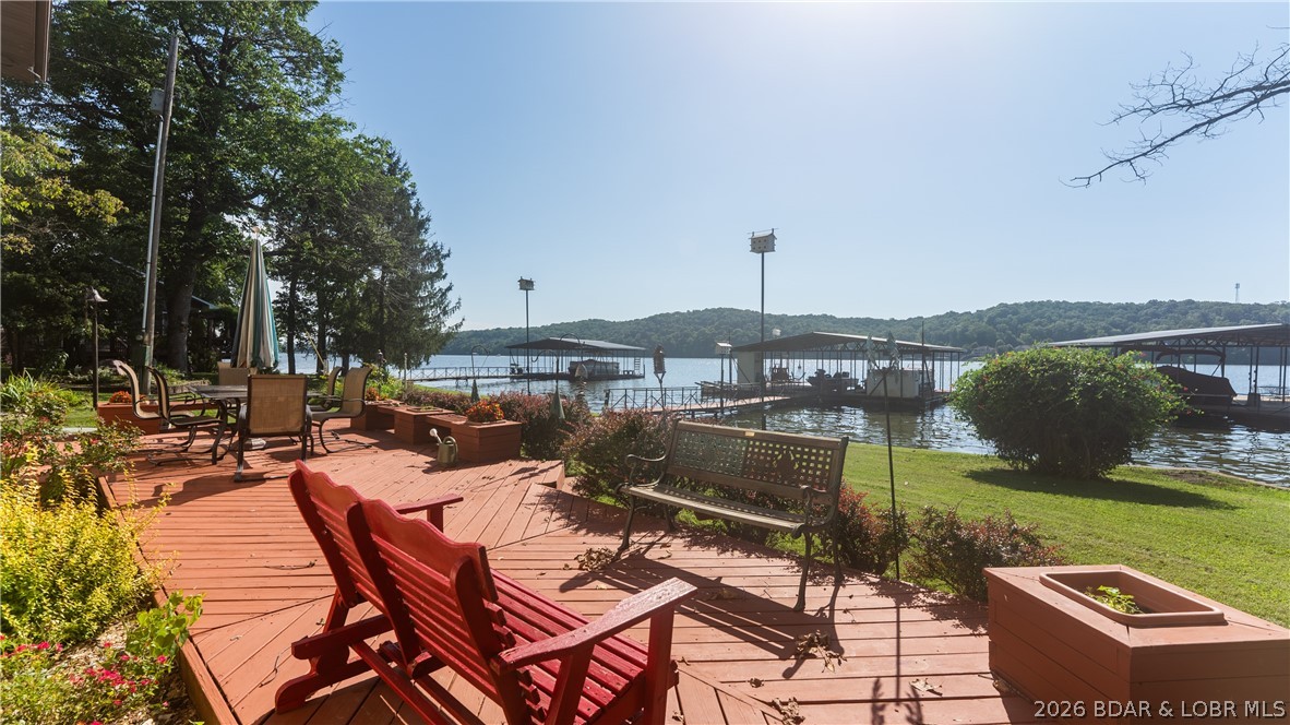 Gorgeous flat lakefront property with no HOA!  This spacious lakefront home offers effortless access to the dock from the patio. The concrete driveway provides ample parking, along with a detached garage, a 15x15 golf cart shed, and a flat entry to your new lake oasis. Ideal for enjoying sunrises and sunsets, this property features a 3-bedroom, 2-full bath home with ample entertaining spaces, including a main level family room, a 10x32 open sunroom, and downstairs main living areas with a large living room. The property includes a lawn, firepit area, patio, and two well-maintained docks. Additional storage is provided by another shed for water toys. The previous garden area could easily be revived for your enjoyment. Walls of windows on both levels allow for year-round lake views. Newer features include a heat pump, septic tank, concrete driveway, electric fireplace, and a new metal roof to be installed in 2025. The heated 26x40 three-car garage includes a workshop area and storage. The seller has enjoyed the neighborhood, the location and the house for many years on a full time basis, and are pleased to pass this along to the next owner with pride!