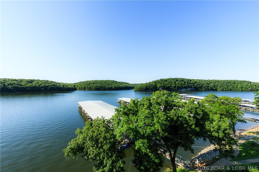 Experience the best of the Lake in this lakefront 2-bedroom, 2-bath condo located at the 5 MM of the Grand Glaize Arm. Nestled within the State Park, this property offers a peaceful setting surrounded by natural beauty while remaining just minutes from shopping, dining, & entertainment. The scenic drive through the State Park sets the tone for the relaxed lake lifestyle you'll enjoy here. Inside, the open-concept layout is designed to showcase the water, with large windows and easy access to the spacious lakeside deck. Step outside and take in stunning panoramic views of the lake. The primary suite offers a private retreat, while the second bedroom and bath provide comfortable space for guests. Whether you're looking for a full-time residence, vacation getaway, or investment opportunity, this condo offers the ideal blend of comfort, convenience, and lakefront living. Furniture included! Park Place on the Lake features excellent amenities, including a pool, clubhouse, playground, boat trailer parking, & beautifully maintained grounds. If you're looking for a place to enjoy everything Lake of the Ozarks has to offer, this condo deserves a spot at the top of your list.