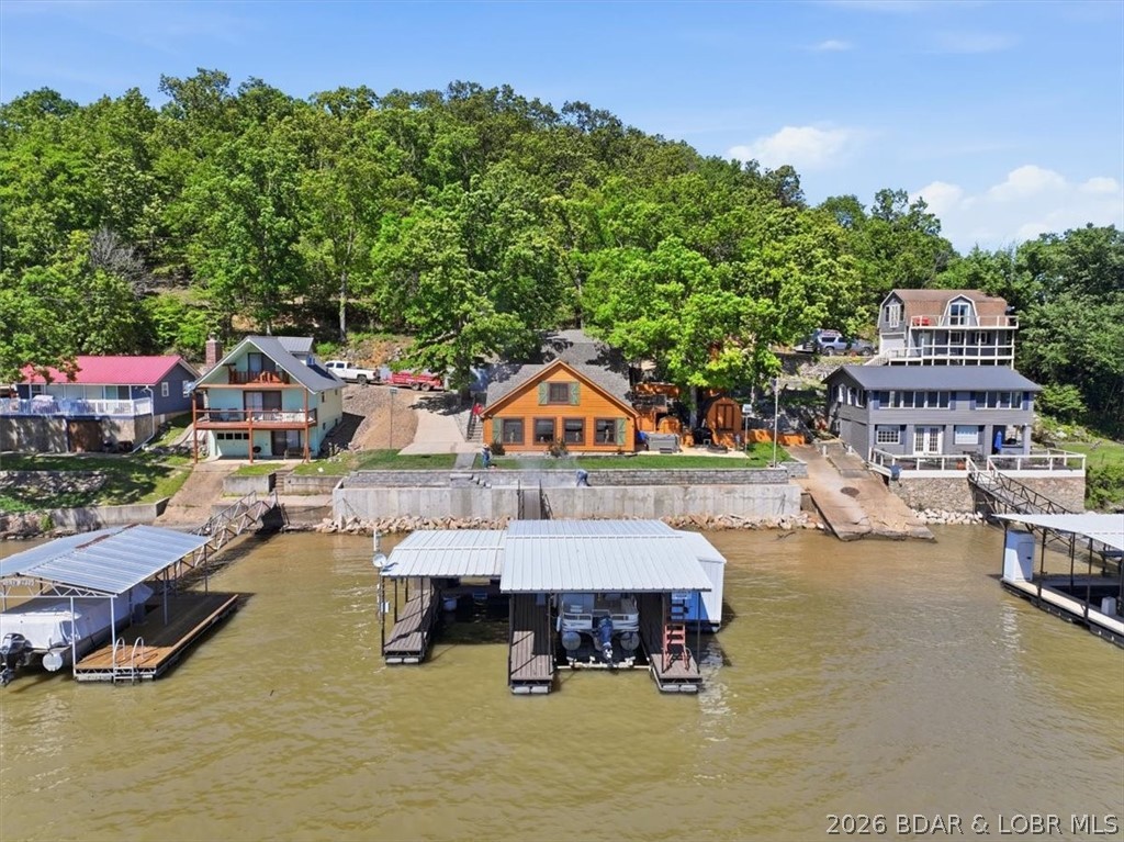 Discover a revitalized lakefront getaway situated at the 61.5 mile marker, where extensive recent updates enhance every corner. This unique property features a comfortable 2-bedroom, 1.5-bath main residence complemented by a detached garage that houses a separate 2 bedroom, 1 bath living area, an ideal setup for giving guests or family their own private retreat. Additionally 2 matching storage sheds are on-site. One is outfitted as a workshop to handle lake projects and house all your aquatic equipment. With more than $180,000 recently dedicated to capital improvements, this home offers significant peace of mind. Key upgrades include a new roof added in 2025 and a 2026 concrete seawall that meets all Ameren permits. The outdoor space is crafted for leisure, with fresh sod, a private multi-slip covered dock, and an entertainment patio complete with a custom propane fireplace and hot tub. Set against the backdrop of expansive main channel views, the estate embodies the spirit of the Ozarks. Perfectly positioned in Central MO, the property is highly accessible, located just 3 hours from Kansas City International Airport and 3.5 hours from St. Louis Lambert International Airport.