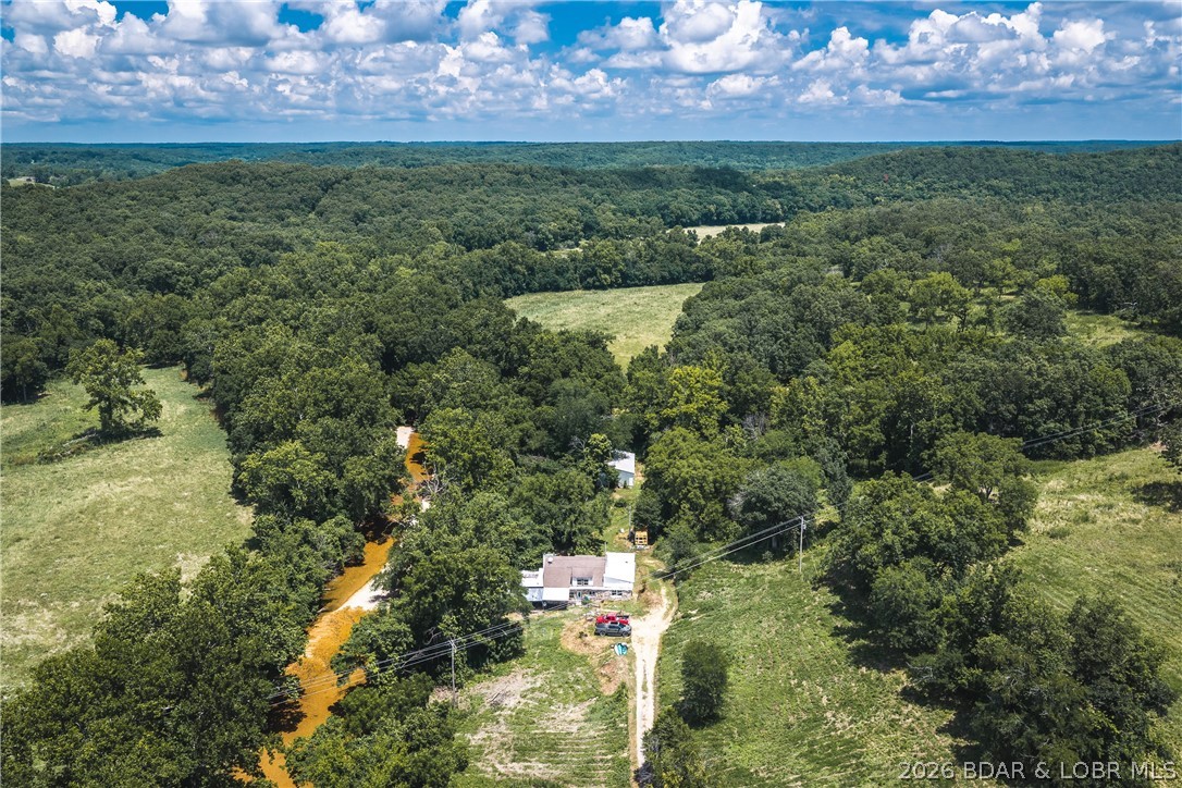 One-of-a-kind properties like this rarely hit the market! Nestled on 5.84+/- acres with an incredible 610+/- feet of private Macks Creek frontage and 550+/- feet of county road frontage, this unforgettable property is packed with character, history, and endless potential. The home, originally built from an old rock barn, is ready for your vision with renovation projects already started, and all remaining building materials convey. Relax on the covered porch overlooking the scenic gravel bar, where the sights and sounds of the creek create your own private paradise. The property also features a converted school bus guest retreat with a wood stove and window A/C, a 30x50 shop with concrete floors and roughed-in plumbing, plus a new septic tank ready for installation. Explore the historic rock cellar, perfect for storage or a storm shelter, two rustic cabins tucked along the creek, a private well, and abundant wildlife throughout. Whether you're dreaming of a weekend retreat, Airbnb, artist's escape, investment project, or truly unique homestead, this property offers an opportunity unlike anything else on the market.