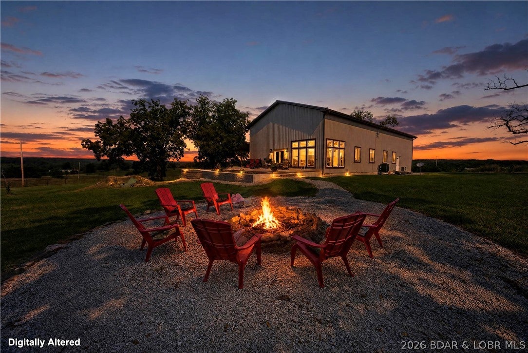 Custom barndominium on nearly 65 acres of mostly pasture ground with mature walnut trees, scattered timber, boarders Rainey Creek, over ½ mile of pipe fencing, and set up for livestock! Whether you're dreaming of a hobby farm, hunting ground, or simply room to roam, this property offers endless possibilities just minutes from Lake of the Ozarks. Built in 2022, this 4-bedroom + loft bedroom, 4.5-bath home was designed to entertain and enjoy the beautiful view. Soaring cathedral ceilings finished in barn metal, walls of windows, a stunning 10' floor-to-ceiling stone fireplace. The kitchen features a 10' granite island, pot filler, and large hidden walk-in pantry. The primary suite offers a soaking tub, walk-in shower and walk in closet. Three more bedrooms are located on the main level, two of which also have private baths. Upstairs includes a second living area/ game room, loft bedroom with a full bath, and finished storage room with 220V. Enjoy the outside under the covered patio off the front of the home, the 26x32 side patio (plumbed for an outdoor kitchen), or fire pit area. Metal siding and roof, spray foam, fiber internet, and no restrictions! Agent is Owner.