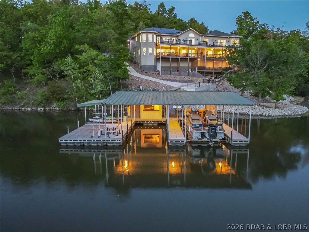 Move-In Ready! Solar Efficient Lake Home with energy bill averaging $80 per month! You don't want to miss this exclusive lakefront home with dock in Linn Creek Cove, MM31, Lake of the Ozarks. This custom furnished home has a 2023 new build with a 2010 fully renovated wing located in the established quiet Cross Creek neighborhood, sitting on 1.74 acres, has a fabulous lakefront view & 621 feet of lake frontage. The home boasts 5670 sq. ft. of interior living space,4 car garage bays with oversized garage area,& add'l parking on the wide, gentle sloped concrete driveway.The main interior floor offers open floor living, vaulted ceiling,stacked stone gas fireplace, chef's kitchen & dining room with hardwood floors. It features a great room, 2 master ensuites, 2 add'l beds, add'l 1.5 baths, & laundry. Lower level boasts family rm, entertainment rm, 3 beds, exercise/bonus rm, office/bedrm, 3 baths, bar room, & dining area. Enjoy your hot tub, wet bar, sitting area, game area, & lakeside firepit. A concrete dock with 2 boat slips, double PWC slip, swim platform, dock bar, & storage area completes the package. A perfect home to enjoy year-round or seasonal with your family and friends!