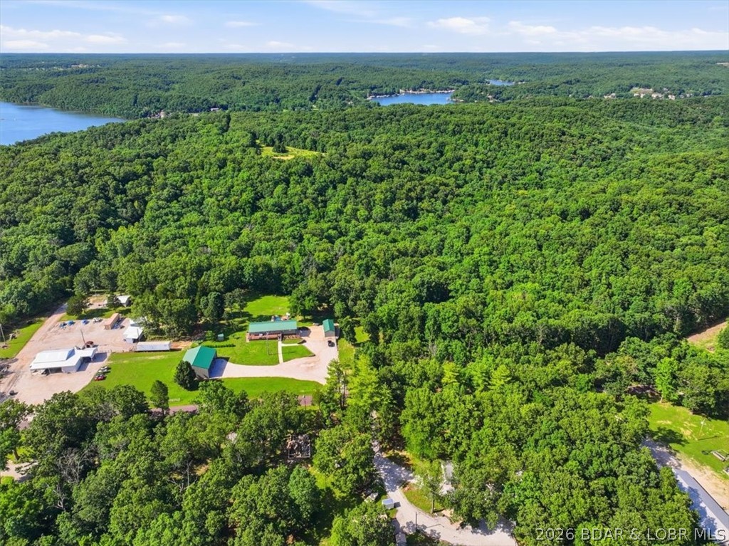 Rare opportunity to own ±78.41 acres at Lake of the Ozarks! This unrestricted property offers the perfect combination of privacy, recreation, and convenience with blacktop road frontage and high-speed fiber optic internet available. The land is a hunter's dream, featuring trophy whitetail deer, wild turkey, four established food plots, and a trail system throughout the property. Whether you're looking for a full-time residence, business opportunity, or hunting retreat, this property checks all the boxes. Built in 2011, the 2,422-square-foot home features 4 bedrooms, 2.5 bathrooms, and a finished walkout basement. Relax or entertain on the large covered patio complete with an outdoor kitchen overlooking the pool and hot tub. Additional improvements include an attached one-car garage, a 16x36 detached garage with two overhead doors, a 40x48 machine shed, and a 30x40 shop with overhead lifts. Located less than one mile from the Gravois Mills public boat ramp, you'll enjoy quick access to the lake! Properties with this amount of acreage, quality improvements, hunting opportunities, and close to the lake are increasingly hard to find. Schedule your showing today!