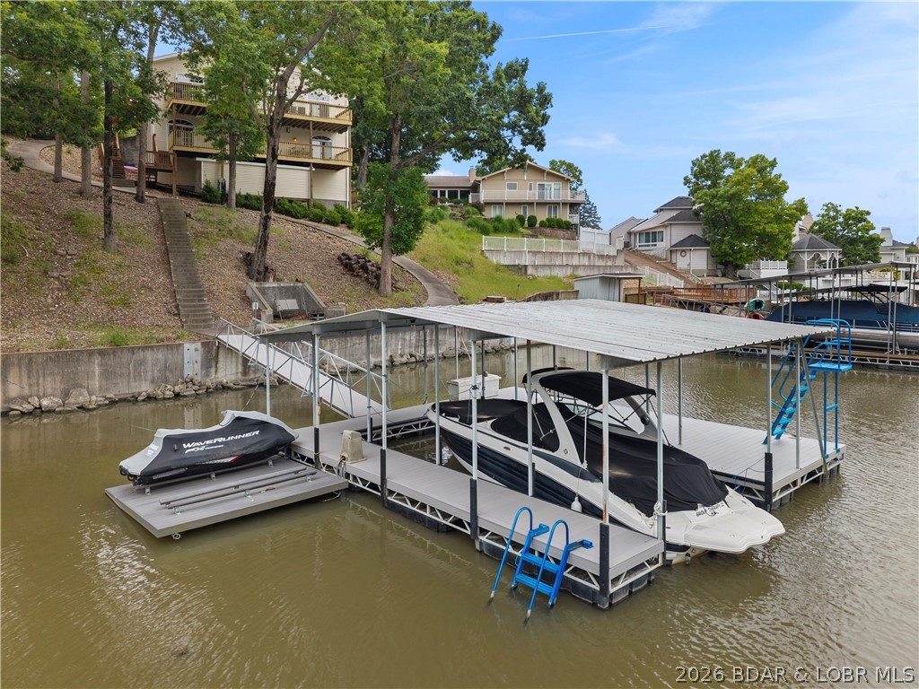 This lake home has all the features you appreciate & have been waiting for! Flat driveway, 3 car garage, maintenance free landscape, cove protection, cart path to dock & BIG main channel views all year round. Inside find easy main-floor living with spacious layout. Step out to oversized deck that's perfect spot to relax, entertain & soak in the endless action out on the lake. Downstairs is set up perfectly for guests with 3 additional bedrooms, a second living space, and a wet bar perfect for game days & night caps. Features like custom cabinets, quartz countertops, wood flooring, the list goes on & on. The best part is having the protection of the deepwater cove with a generous 112 feet of shoreline. Concrete dock set up for hours of fun and includes dual PWC lift, swim platform to swim, fish, lay out & 12x28 slip. Step right off dock to a concrete seating area, perfect for gathering around fire. Inviting neighborhood that makes stellar full time residence but also allows short term rentals. So what are you waiting for? This is one of the good ones you don't wanna miss!