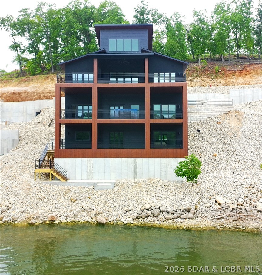 Experience luxury lakefront living at the 3 Mile Marker of Lake of the Ozarks.  Designed with remarkable attention to detail, the home showcases custom black and walnut cabinetry, marble countertops, premium appliances, and a stunning glass pivot entry door. Two primary suites provide spacious retreats with custom showers and walk-in closets, while the upper-level lounge offers additional living space complete with custom cabinetry and a beverage refrigerator.

Built for entertaining, the lower level features a custom bar with live-edge walnut accents and direct access to the lakeside deck and dock. Expansive covered composite decks and accordion-style Pella doors create a seamless indoor-outdoor experience, allowing you to fully enjoy the beautiful lake views. Additional features include an electric fireplace, heated and cooled two-car garage, luxury finishes throughout, and a thoughtfully designed layout that blends comfort, functionality, and upscale waterfront living in one exceptional package.