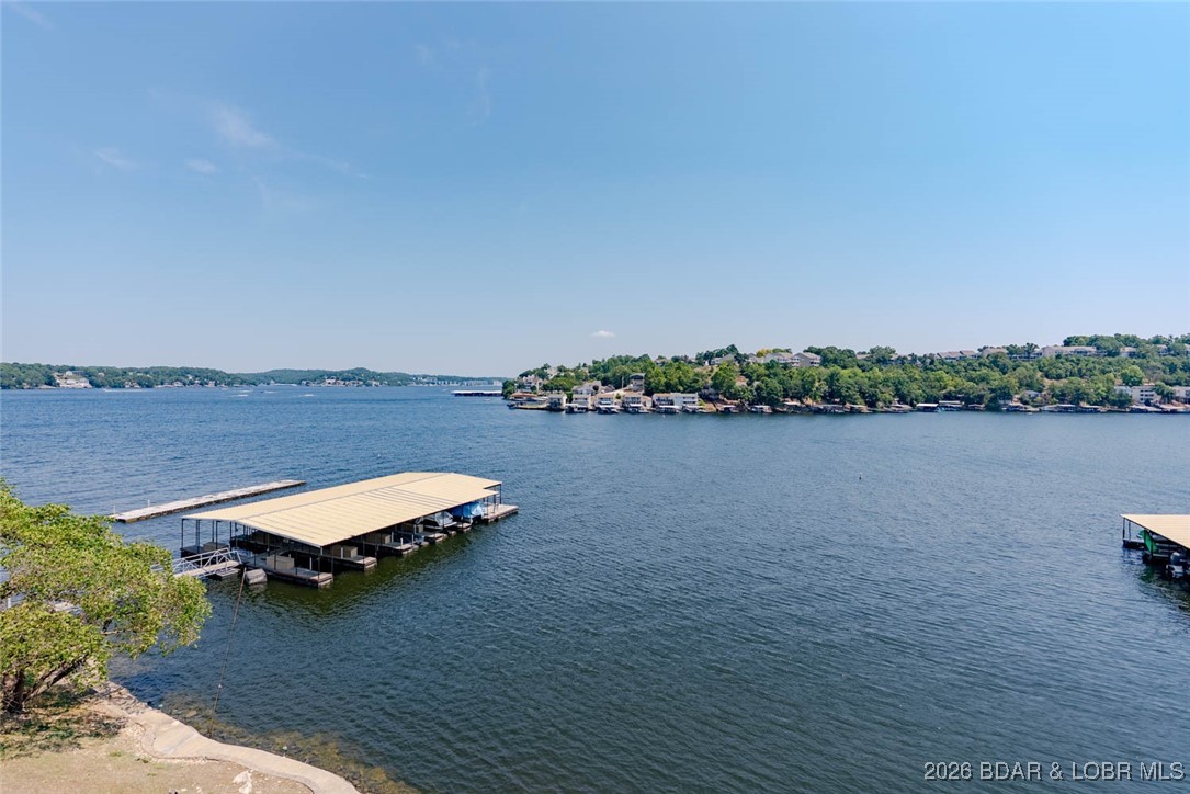 Check this beauty out! This well-cared-for, turn-key unit features stunning main channel views with cove protection for your boat slip and two PWC slips. The walk-in design provides easy access, with the dock located just outside your door—perfect for effortless lake days. Beautiful flooring, updated paint, and refreshed bathrooms complement the stylish furnishings, making this condo move-in ready from day one. The layout offers charm and character with architectural angles that create great flow for entertaining and lake living. The primary suite features a double vanity, walk-in closet, walk-in shower, and private water closet. A lakeside guest bedroom sits adjacent to an updated full bath. The kitchen overlooks the water and includes a full-size laundry room. Enjoy large interior storage area and new HVAC system. Complex is meticulously maintained and offers a large swimming pool, clubhouse, and tennis court. Convenient by land and water. Enjoy breathtaking sunrises from the oversized covered deck. Boat hoist & one PWC hoist included. Furnishings included.Owners to pay $25,000 special assessment at closing for deck replacement.