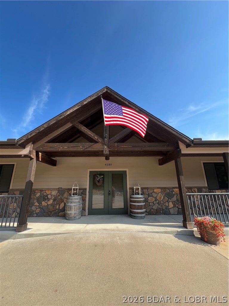 A unique, multi-use commercial property with tremendous space, character and opportunity! Located in the heart of Osage Beach, this impressive 7,798-square-foot commercial lodge is perched on a hill with Lake of the Ozarks views and features wood beams, stone accents and expansive outdoor decks. Formerly a resort welcome center, the property offers a spacious reception and check-in area, private office space, a large conference and gathering area, a commercial-support kitchen, restrooms on both levels, and a walkout lower level. The full laundry facility has multiple washers and dryers and is currently leased for resort turnover and cleaning operations, while a Realtor occupies the front office area—providing existing income potential. Zoned C-1B Commercial Lodging District, this distinctive property offers flexibility for lodging, hospitality, office, event, meeting or other commercial uses, subject to applicable approvals. Exterior features include LP® SmartSide® siding and trim, cultured stone veneer, Fiberon® composite decking and powder-coated aluminum railings—creating a virtually maintenance-free exterior.