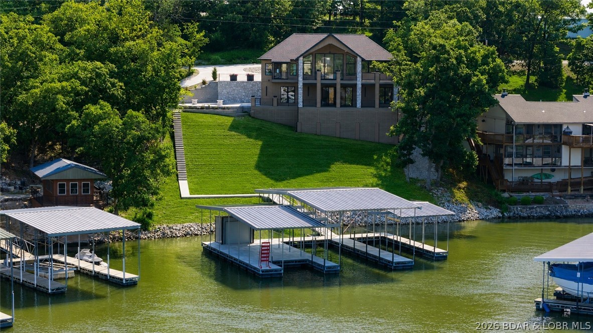 Luxury lakefront living w/ high-end finishes, exceptional outdoor spaces, & ability to nightly rent. This 5BR, 5.5BA home offers 3,800SqFt & is offered fully furnished. The design is highlighted by ~13ft ceilings in the living room & an 11ft Quaker aluminum sliding door that fully retracts, seamlessly connecting to the covered lakeside deck sporting massive lake views. The chef's kitchen features quartz countertops, gas range, custom range hood, dual refrigerators, SS appliances, & a butler's pantry. The main level also includes the primary suite, guest bathroom, & laundry, while the lower level offers a second entertainment space, four more bedrooms, four bathrooms, a second laundry room, & a game/lounge room featuring built-in queen bunk beds. Outside, the nearly $450,000 gunite pool w/ fire bowls & dock package creates the ultimate lakefront experience. The new dock includes a 16x44 slip, 12x34 slip, dual PWC slips, and huge swim platform. More highlights include two levels of composite decking, cove location w/ calm water, a flat driveway, insulated garage w/ mini-split, plentiful shoulder street parking, & premium Diamond Kote LP SmartSide siding. View this today!