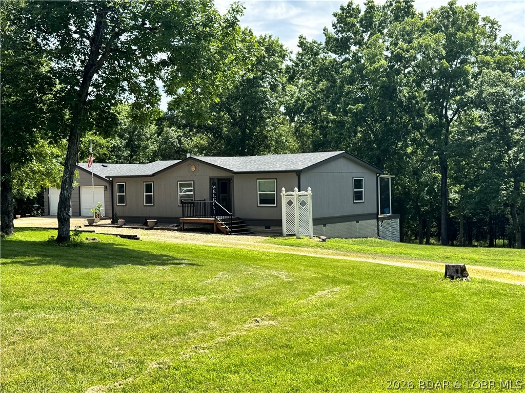 Nature lovers will appreciate this one-level manufactured home situated on 3.1 partially wooded acres. Surrounded by mature trees and abundant wildlife, this peaceful property offers privacy and a beautiful natural setting. Spend your mornings relaxing on the screened-in porch while enjoying the sights and sounds of nature. With plenty of room for children to play and explore, this property is perfect for those seeking space and tranquility. Conveniently located close to town and the Lake of the Ozarks, this home features 3 bedrooms, 2 bathrooms, and an attached two-car garage with ample storage space.