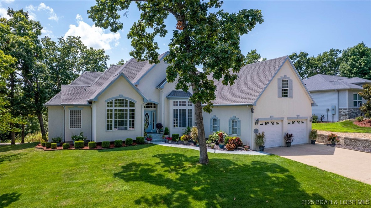 Contractor-built home with attention to detail in The Estates Subdivision! This main-level living residence features soaring ceilings, hardwood floors, and gas fireplace in great room. Formal dining room and living area is great for entertaining. Kitchen offers updated countertops, stainless steel appliances, abundant cabinetry, and a breakfast area that opens to expansive decks with a seasonal lake view. Oversized laundry room includes a utility sink. Two primary ensuites feature heated bathroom floors, custom-tiled walk-in showers, double vanities, and oversized walk-in closets with custom built-ins. Two additional bedrooms, full bath and a half bath. Lower level includes a 3rd oversized garage with street access, heated and cooled, perfect for storage, or workshop. Highlights include a two-car upper garage with new doors, and plenty of storage. Recent updates include water heater, water softener, and air conditioning system. Community amenities include pool with bathhouse, central sewer, trash service, basketball court, and a wonderful neighborhood for walking and socializing. Lake access is available with a 14x40 boat slip offered separately for $58,000. Call for details!