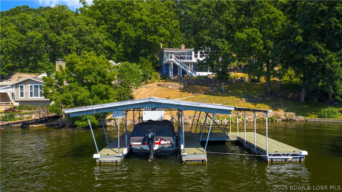 287 Shoe Lace Drive in Camdenton brings Lake of the Ozarks living to life with 140 feet of shoreline and spectacular lake views that steal the show from sunrise to sunset. This updated 1774 sq. ft. 3-bedroom, 2-bath retreat offers comfortable one-level living with bright, welcoming spaces, LVP flooring, Cambria Quartz countertops, refreshed cabinetry, newer appliances, updated windows, a walk-in shower, and a cozy woodburning fireplace. Step outside and choose your favorite place to unwind among the covered and open decks, patio, porch, and lakeside gathering areas made for morning coffee, sunset dinners, and memorable weekends with family and friends. The 2-well covered dock features 10x30 and 10x20 slips, a boat hoist, electric, updated decking, and an ice breaker. Rentals are allowed, creating possibilities for a personal lake escape, vacation rental, or investment property. A walkout storage basement, carport, shared well, and new engineered septic installed in June 2026 complete this inviting lakefront package.