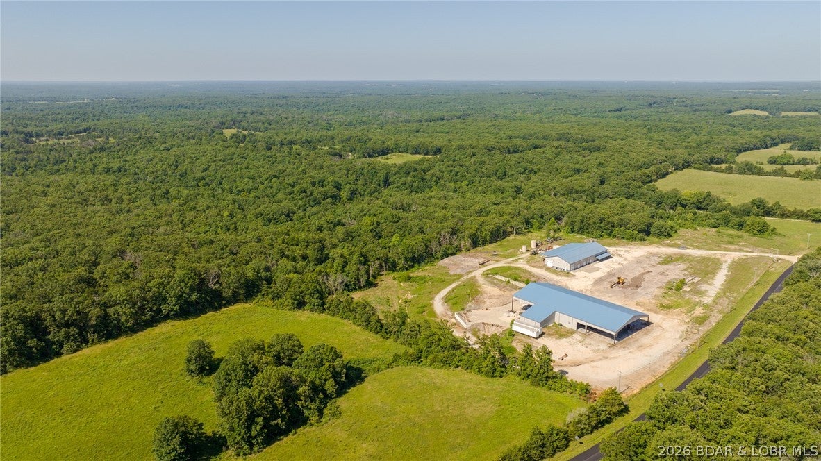 RARE COMMERCIAL/INDUSTRIAL COMPOUND ON 40± ACRES! Offering approx. 24,000 sq ft between two substantial buildings, 3-phase electric and paved State Rd NN frontage, this property is built for serious business with room to grow. The 15,000 sq ft industrial building features a concrete loading dock, floor drains, covered lean-to with concrete floor and easy access for semis and large trucks. The second 9,000 sq ft heated/cooled building offers 7 oversized doors, 18' sidewalls, concrete floors, spray-foam insulation, exhaust system, loft storage, fiber internet and 2 RV hookups, plus impressive 3BR/2BA living quarters with custom hickory cabinetry and live-edge cedar countertops. Expansive graveled work and parking areas provide space for trucks, equipment, outdoor storage or future expansion. Wooded acreage, trails, abundant wildlife and a wet-weather creek add versatility. Ideal for manufacturing, distribution, contractor headquarters, equipment operations, warehousing, investment or a private business compound.