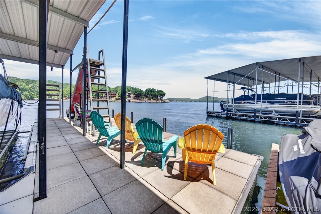 LOCATION, LOCATION, LOCATION! Experience the best of Lake of the Ozarks with this 3-bedroom, lakefront home tucked in a protected no-wake cove with big lake views and quick access by both land and water. Enjoy paved roads to your door, parking for 5-6 vehicles, and rare elbow room between neighboring homes. Inside, walls of windows capture the view, while the updated kitchen with additional counter space & beverage refrigerator, beautiful bamboo flooring, and spacious lower-level living area offer comfort and style. Step onto the expansive lakeside new trek deck  & aluminum railings overlooking the water.  Head down to the oversized concrete 2-well dock with 12x40 & 12x32 slips,10,000# remote lift, deep water, perfect for today's larger boats. 2 PWC slips, swim deck, Large dock shed, dock locker & SLIDE!!!. Whether you're looking for a full-time home, weekend retreat, or investment property, this well-maintained lakefront gem delivers the location, views, dock, parking, and LAKE lifestyle!
