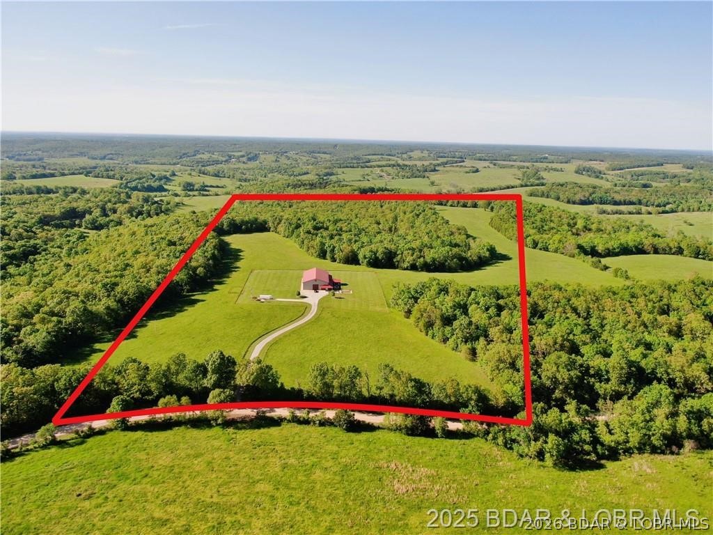 Stunning 80-acre Dream Farm perfect for farming, recreation, and ATV adventures — and just 30 minutes from the Lake of the Ozarks resort area. Built in 2017, the custom 1,788 sq ft Shouse features granite finishes, geothermal heated floors, fireplaces in both ensuite bedrooms, and a jaw-dropping 1,000 sq ft glass-enclosed Three Seasons Room. The 5,000 sq ft heated/insulated shop includes 14’x14’ doors for RVs and equipment, plus a full RV pad with hookups. Enjoy two spring-fed ponds, abundant wildlife, and wide-open spaces. This rare find blends upscale rural living with serious income or lifestyle potential. Looking for a business opportunity? This property is ideal for offering guided hunting and fishing experiences — or simply enjoying it as your own private paradise