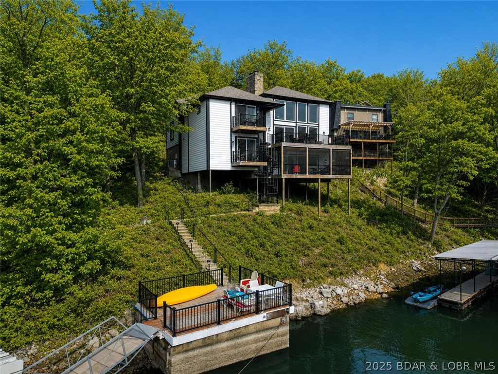 Exceptional lakefront investment opportunity in the heart of Osage Beach! Located at the 25MM within Tan-Tar-A/Margaritaville Lake Resort, this property is a proven performer for short-term rental income, or a perfect family getaway! Offering over 4,200 sq ft, this spacious home features 4 large bedrooms (three with two queen beds), 3 bathrooms, and a rarely seen open floor plan for the neighborhood. The beautifully updated kitchen and dining area flow seamlessly into a HUGE vaulted living room highlighted by a stunning floor-to-ceiling rock fireplace. The main level includes 2 bedrooms and 2 bathrooms, while the lower level offers 2 additional bedrooms, a full bath, and flexible entertaining space—ideal for large groups and rentals. Outdoor living shines with three decks, a screened porch, a permitted martini deck, and a private dock, perfect for soaking up the Lake lifestyle. Located in Tan Tar A Estates within the Margaritaville Resort complex, owners and guests enjoy amenities galore, making this a highly desirable rental destination. A rare opportunity to own a lakefront property that combines rental potential, prime location, and unforgettable Lake of the Ozarks living.