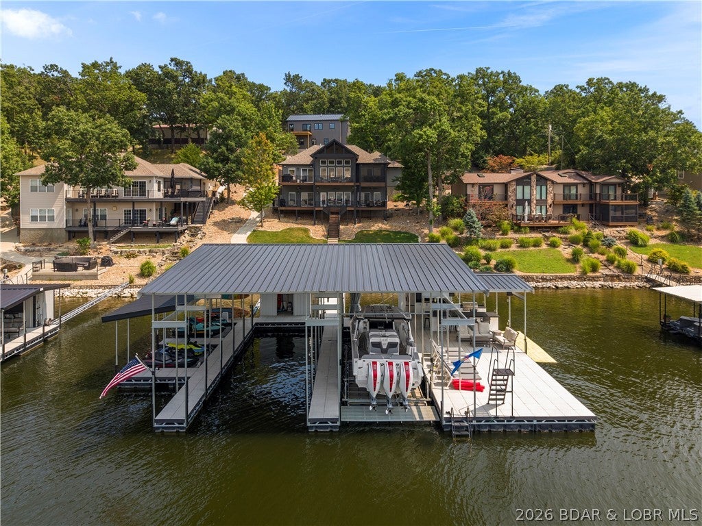 Perfectly positioned in a protected cove with breathtaking main channel views, this exceptional lakefront retreat offers the ideal blend of luxury, comfort, and investment potential! This beautifully updated 6-bedroom,4.5-bath home is located in the heart of the lake between Porto Cima & The Villages, providing easy access to premier dining, shopping, golf, and entertainment by both land and water. Offered fully furnished and turnkey, it's ready to enjoy from day one. The open main-level living area showcases a dramatic wall of windows framing spectacular lake views, while the lower level features three bedrooms, a spacious family room, wet bar, and walkout patio. Outside, the dream dock is unmatched with deep, calm water, a 16'x48' slip, 14'x44' slip 4 PWC slips, two swim ladders, high dive, and an incredible lakeside bar/kitchen designed for entertaining. A screened porch, attached 2-car garage, and brand-new detached garage with three additional bays and guest quarters that include 2 beds/1bath, full kitchen & laundry above provide exceptional space for family and guests. Nightly rentals are permitted, making this a rare opportunity for both luxury living and income potential!