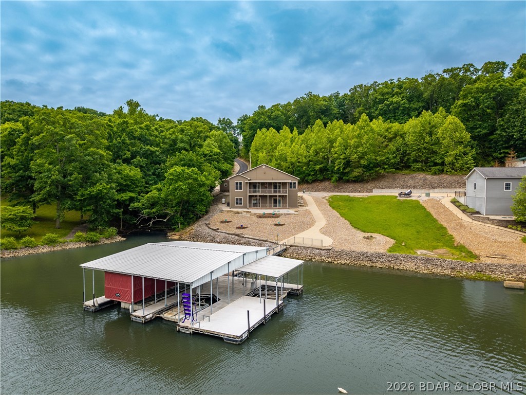 Rare opportunities like this do not come along often. Located just off Duckhead near the beginning of HH, this home offers the hard-to-find combination of a private drive, flat lot, flat driveway, and true no-step access all the way to the dock. With plenty of parking, a golf cart path to the water, and a quiet cove setting, this property was designed for easy lake living. Enjoy 100 feet of pristine shoreline and a lake-ready setup with a 2-well dock, 2 boat hoists, a touchless boat cover, and 2 PWC hoists. Whether you enjoy boating, swimming, paddleboarding, or simply relaxing by the water, this property makes it easy to enjoy every part of lake life.  The home features 4 bedrooms, 3 full baths, with 2 bedrooms on the main level. Inside you will find hickory floors, an upgraded kitchen, 2 fireplaces, 2 laundry rooms, and a lower-level wet bar perfect for entertaining family and friends. Two decks provide great outdoor space, while the detached shop offers room for a workshop, golf cart, ATV, or additional lake storage. Schedule your private showing today and see in person what makes this home such a special find.