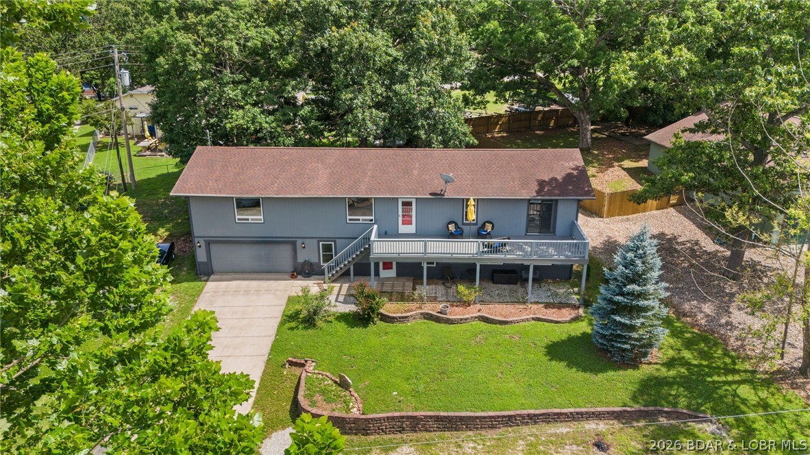 Affordable lake living with the features buyers are searching for—lake views, a 10x20 boat slip, community pool, boat ramp, and plenty of space for family and guests. Located in the desirable Fawn Valley subdivision, this 4-bedroom, 3-bath home offers a flexible floor plan with multiple living areas and a spacious oversized 2-car garage with room for storage, hobbies, or a workshop. The main level features an open living, dining, and kitchen area that flows to the lakeside deck and fenced backyard, creating the perfect setting for entertaining, pets, or enjoying the view. The primary suite, two additional bedrooms, and a full bath are conveniently located on the upper level, while the walkout lower level offers a second living area, fourth bedroom, and full bath—ideal for guests, a home office, or recreation space. Recent improvements include exterior paint, updated flooring, lower-level windows, and deck renovations. While there is opportunity for a new owner to add their own updates and personal touches, the value here is hard to ignore. Enjoy paved roads, high-speed internet, excellent community amenities, and easy access to Lake of the Ozarks, with a gorgeous lakeside deck.
