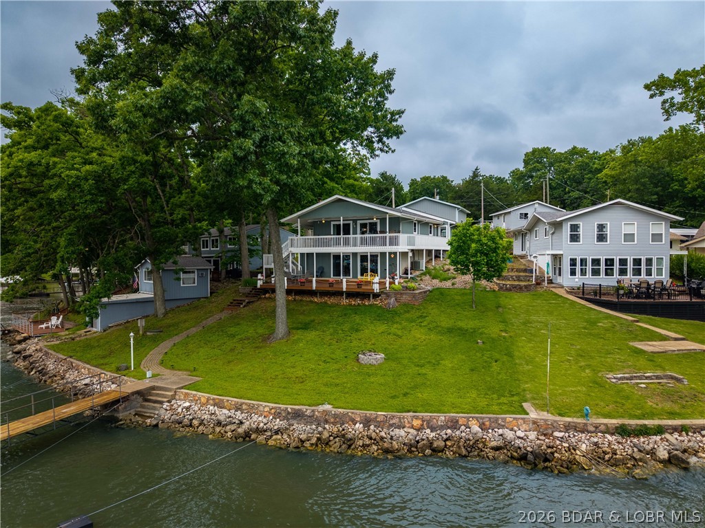 Discover the perfect blend of lakefront relaxation and entertaining with this beautifully maintained home featuring main channel views, cove protection, and a gentle lot to the water. Offering 3 bedrooms, 3 full baths and neutral décor throughout, this property is ideal for full-time living, weekend escapes, or investment potential at Lake of the Ozarks.The spacious outdoor entertaining areas are designed to maximize lake life, whether hosting guests, grilling out, or simply enjoying the peaceful setting. The dock features a 10x24 boat slip with a large sun pad area, providing the perfect place to relax by the water while enjoying protected cove conditions and easy boating access to the main channel. Additional highlights include a brand new detached 2-car garage, shared well, sewer district access, and survey on file for added convenience. The combination of gentle access, beautiful views, deep water, massive dock profile, and functional outdoor space makes this property a rare find. Conveniently located near lakefront attractions, dining, and entertainment, this home offers everything needed to enjoy the Lake of the Ozarks lifestyle year-round.