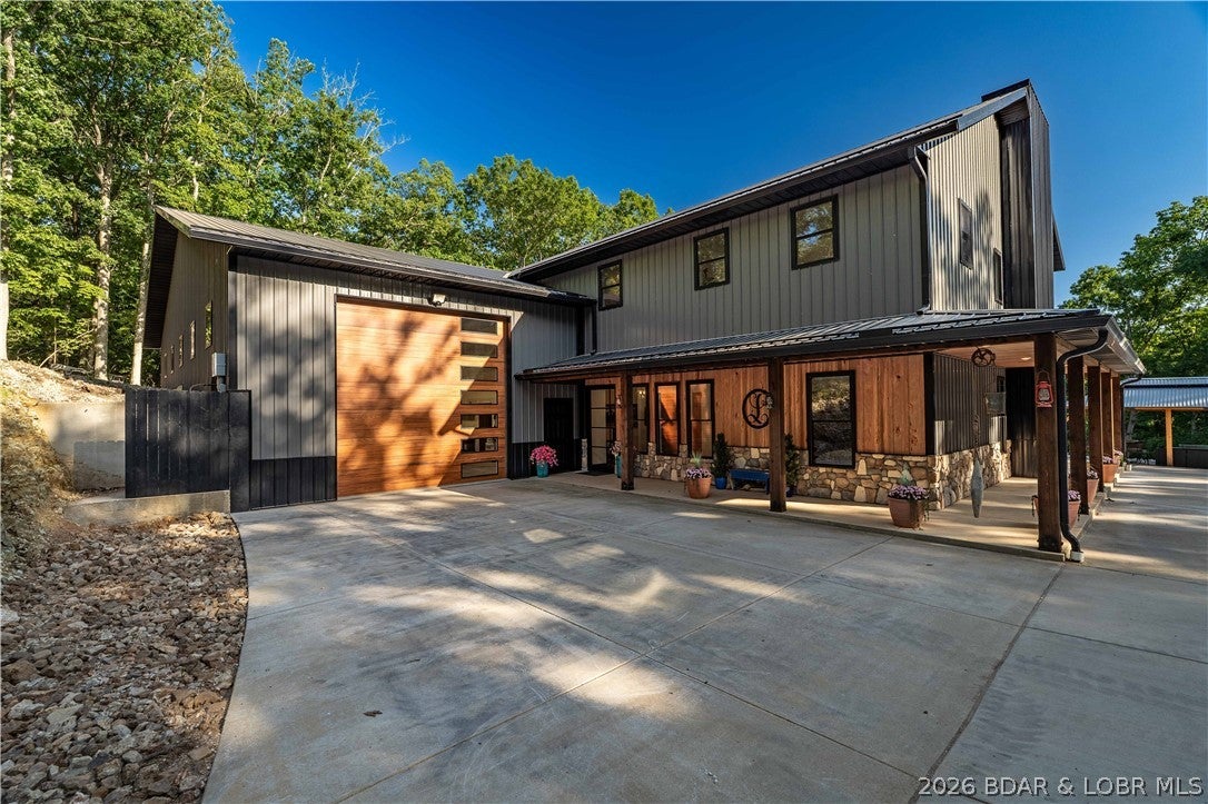 An exceptional custom lakefront estate offering rare privacy, refined craftsmanship, and modern luxury across 125 feet of shoreline and over three wooded acres—a setting of scale and seclusion increasingly uncommon at Lake of the Ozarks.
Encompassing approx. 6000 square feet, the residence blends contemporary design with warm rustic sophistication. A dramatic wall of windows frames, sweeping lake views, complemented by a floating staircase, custom hickory cabinets, solid hardwood doors, and a chef’s kitchen.
Designed for elevated living and entertaining, the home offers multiple gathering spaces including an artist loft, music room, golf simulator or theater, exercise room, and climate-controlled gun room. Outdoor living is equally refined with slate patios, fire features, and a private dock set within a tranquil, wooded landscape.
An attached 60’x30’ RV garage with 16’ ceilings, 50-amp service, and dump station adds an additional 1800 sq ft and completes this rare lakefront offering—where luxury, recreation, and privacy are seamlessly balanced.