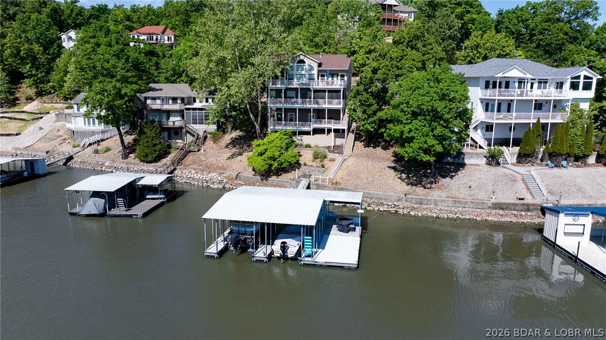 The moment you walk through the door, the view steals the show. Perfectly positioned on the 1MM of the Big Niangua, this 3 bed, 4 bath lakefront home offers over 2,800 s.f. but lives much larger thanks to soaring vaulted ceilings, walls of windows, and an open layout designed to pull the outdoors in. Warm hand-scraped hickory floors, tasteful updates, and inviting living spaces create the ideal blend of comfort and lake style. The kitchen opens seamlessly to dining, living, and multiple outdoor entertaining areas including screened and open decks on both levels—all focused on that HUGE water view. The spacious primary suite is beautifully updated, while the lower level offers an oversized family room, wet bar, office/game/exercise space, two guest suites, & two additional full baths, making it ideal for hosting family & friends. Outside, enjoy a large concrete lakeside entertaining area plus a 2-well concrete dock ready for full lake fun. Located in an area of beautiful homes, just minutes by water to Miller's Landing, Larry's on the Lake, and The Fish and Company. 2 car garage was turned into a bunk room for grandkids w/mini split added, but can easily be converted back to garage!