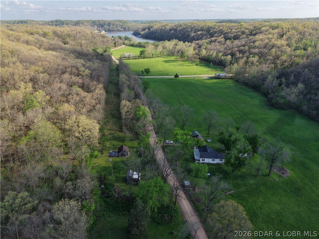 Live the best of both worlds—peaceful country living just minutes from the lake. Spend your mornings on the water and your evenings watching the sunset from your own land. This 80-acre property offers a great mix of open pasture and mature timber, with approximately 15 acres of fenced pasture ready for livestock, horses, or hobby farming. Established trails, a food plot, and abundant wildlife make this a true hunting retreat— trophy deer, turkey, and mushrooms right out your back door. A beautiful natural spring winds through the property into Proctor Cove, adding to the peaceful setting. The home feels warm and inviting from the moment you walk in. Featuring 1 bedroom, 1 bathroom, and two flex rooms, it offers flexible space for guests, a bunk room, or office. The kitchen and comfortable living room make it easy to gather and unwind. You’ll also find an established garden area and a shop with concrete floors and electric as well as 3 barns for extra storage.Whether you’re looking for a weekend lake escape, hunting property, or full-time home with a one of a kind setting, this one has it all. Schedule your showing today and start living the lake life with land to call your own.