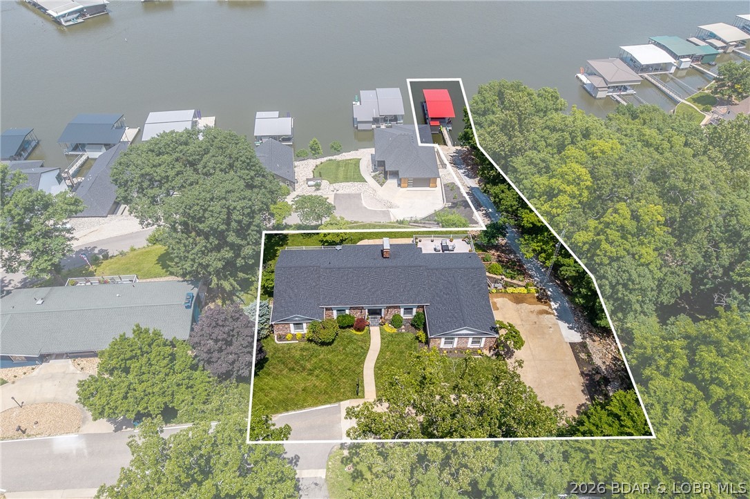 Classic brick ranch meets modern luxury in the heart of Osage Beach! This beautifully reimagined 6-bedroom, 4.5-bath home offers over 5,700 square feet of living space and breathtaking lake views. Sunlight pours through expansive windows, highlighting new engineered hardwood floors and an inviting layout. The stunning kitchen features custom two-tone cabinetry, quartz countertops, an 8-foot waterfall island, black stainless Café appliances, and elegant finishes. The main level also offers a formal dining room, sitting room, spacious living area, guest bedrooms, and an incredible primary suite w/ attached bath offering heated tile floors, soaking tub and oversized tiled shower. The lower level is built for entertaining with a massive family room, custom wet bar, and a hidden speakeasy behind a bookcase complete with a walk-in vault room and concealed wall safe. Additional bedrooms, updated baths, and a private lakeside en-suite provide plenty of room for family and guests. Outside, a newly poured concrete cart path leads to 30 feet of lakefront and a brand-new 22x50 concrete dock with a 14x40 slip in deep water. Close to everything Osage Beach has to offer! SIDE X SIDE NOW INCLUDED