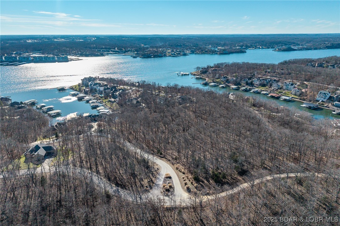 Surrounded by mature trees and natural Ozarks beauty, this wooded lot at The Villages at Shawnee Bend offers a peaceful, private setting within one of Lake of the Ozarks’ most distinguished communities. From the moment you arrive through the grand waterfall entrance, the neighborhood’s upscale character is clear. Residents enjoy access to a beautifully appointed clubhouse, resort-style community pool, championship tennis courts, and pickleball facilities, along with parks, and playgrounds. Paved roads and underground utilities make building seamless while preserving the natural landscape. Ideal for a custom home or lake retreat, this wooded homesite blends serenity, luxury, and an active lake lifestyle.