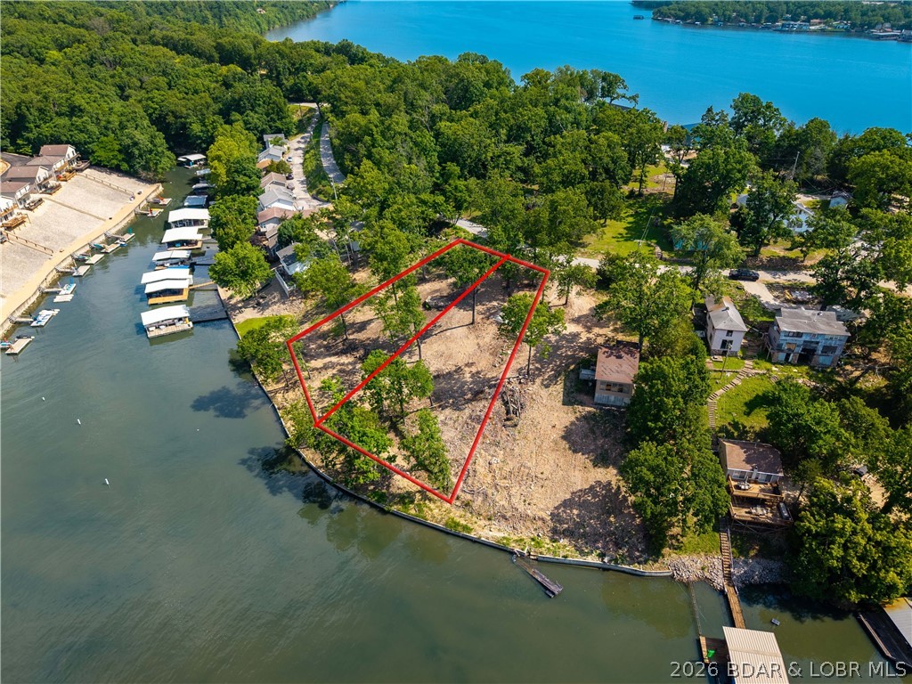 Rare opportunity to build your dream lakefront home in one of the most desirable areas of Lake of the Ozarks! This exceptional lot offers over 100 feet of lake frontage and gentle topography, making the building process easier and more cost-effective while providing excellent access to the waterfront. Enjoy deep water, ideal for boating, swimming, and year-round dock use. Conveniently located at the 14 MM, this property offers the perfect blend of privacy and accessibility. By water, you're just minutes from many of the lake's most popular waterfront restaurants, entertainment destinations, and attractions. By land, you'll appreciate the quick access to shopping, dining, golf, and everyday conveniences. City water and sewer are available, eliminating many of the challenges often associated with lakefront construction. Whether you're envisioning a full-time residence, vacation getaway, or future investment property, this lot provides the ideal setting to bring your vision to life. With over 100 feet of lake frontage, deep water, gentle terrain, and a prime central location, this is a rare opportunity to create the custom lake home you've always wanted at Lake of the Ozarks.