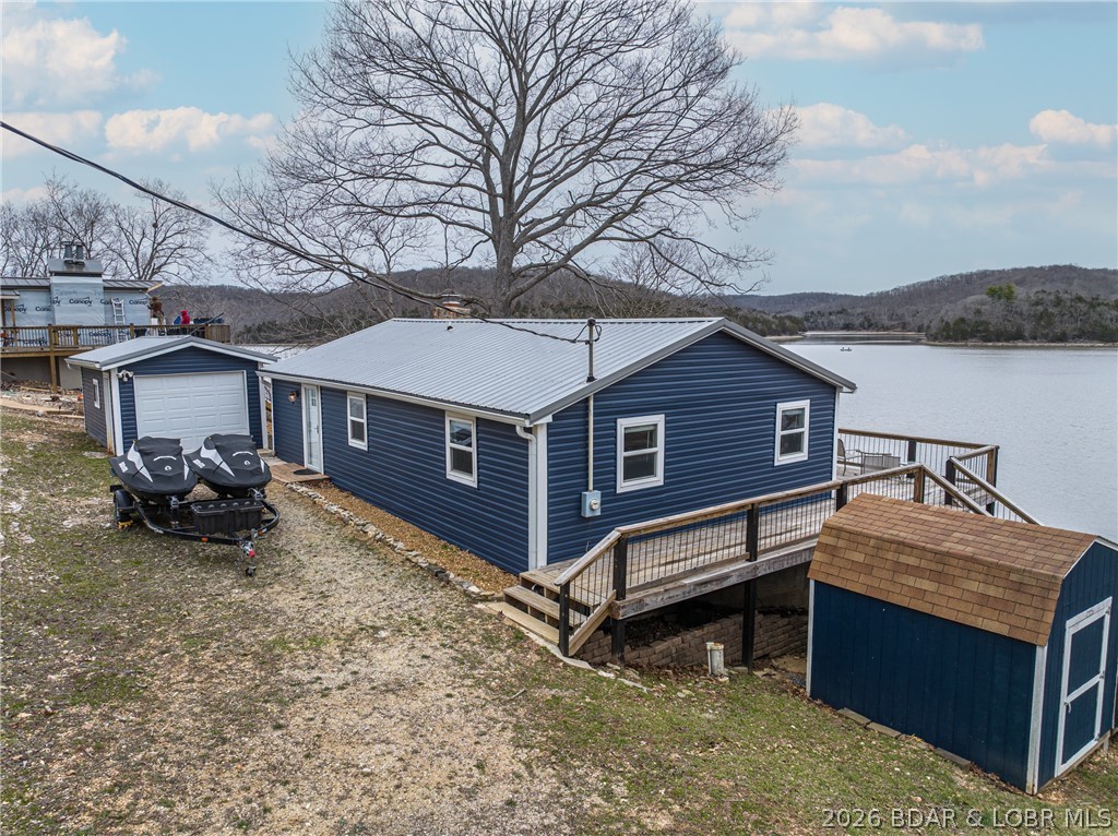 Welcome to the quiet side of Lake of the Ozarks. Set along 160’ of shoreline with deep water, this lakefront property offers a combination of usable outdoor space and a completely updated home. This 3 bedroom, 1.5 bathroom home spans 1,200 sq ft with vaulted ceilings, an open layout, and inviting living area. The living room has a new high efficiency fireplace insert and features double sliding glass doors that open directly to the large lakeside deck with an incredible view of the 66MM. Outside, a spacious lakeside deck overlooks the water, while the almost new private dock features steel and concrete construction with two slips (12x28 and 10x28), a swim platform, and a bar/storage area. A long driveway provides plenty of extra parking. Additional features include a detached garage, a storage shed, and a dog kennel. Need more garage space? This big lot allows you to build an additional garage or shop. The home has been updated inside and out and has a new 1000 gallon septic tank as well. This property is ideal for those who prefer a more private, relaxed setting. Be sure to watch the virtual tour!