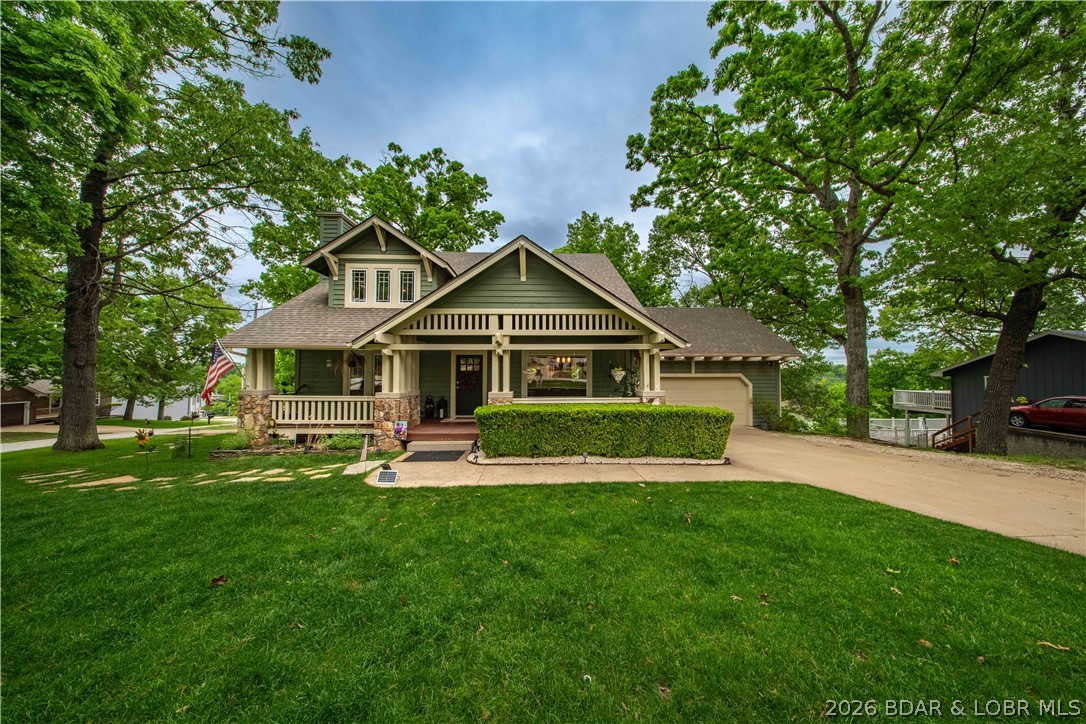 DURING THE JULY 4TH STORM, THIS HOME WAS NEVER OUT OF POWER BECUASE OF THERI STANDBY WHOLE HOUSE GENERATOR!  THAT'S A HUGE PEACE OF MIND DURING SUMMER AND WINTER STORMS! Welcome to this 4-bedroom, 3.5-bath Craftsman home in the heart of Osage Beach—where summer lake days and cozy winter nights come together beautifully. Spend your summers soaking in peaceful lake views from the back porch, cruising out from one of your two boat slips, or enjoying the community pool, tennis courts, and boat ramp. Surrounded by mature trees, this property offers a serene setting that feels like your own private retreat. As the seasons change, the home invites you in with a warm, cozy fireplace and comfortable living spaces perfect for gathering with family and friends. Thoughtfully maintained with a newer roof (3 years old), two HVAC units, and a whole-home Generac generator, you’ll enjoy comfort and peace of mind year-round. The heated 2-car attached garage plus an additional lower-level garage is ideal for a workshop, storage, or golf cart. A sprinkler system keeps the front yard looking its best. Located just minutes from lakefront restaurants, the hospital, shopping, and more—