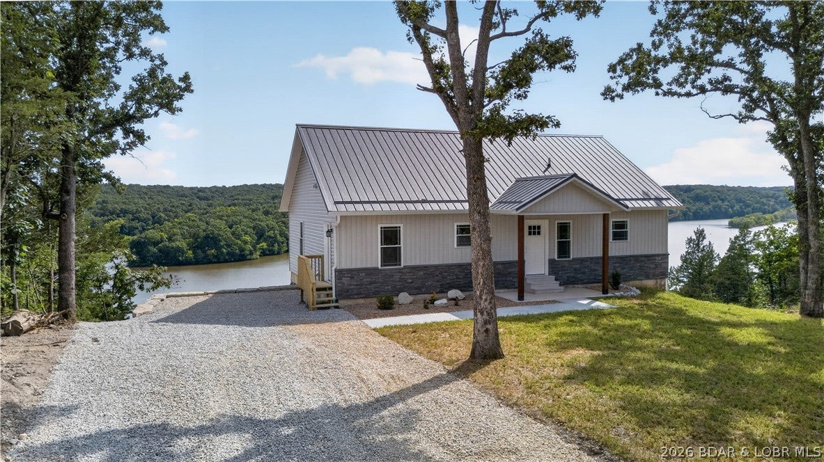 New construction waterfront home at the 79 Mile Marker of the Lake of the Ozarks! From the moment you arrive, the incredible views are sure to catch your attention. Enjoy nearly 180-degree views overlooking the Cole Camp Creek arm of the lake, visible from nearly every window along the back of the home and from the large covered deck. The main level features 2 bedrooms, 2 full baths, and a convenient mudroom with washer and dryer. The spacious open-concept kitchen and living area is designed to take advantage of the views, while the beautifully finished kitchen offers plenty of cabinetry and workspace. Downstairs you'll find an additional bedroom, full bath, kitchenette, and a large flexible space perfect for a rec room, entertaining area, or potential additional bedroom. Step outside to the covered concrete patio and take in even more incredible lake views. The exterior features attractive vinyl and stone siding, a metal roof, and a large driveway with plenty of parking. With approximately 100 feet of waterfront and space for a future shop or outbuilding, this property offers an outstanding combination of new construction, space, and waterfront living!