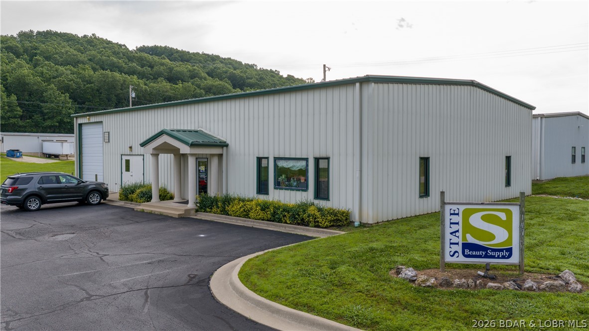 Position your business for success in the highly desirable Linn Creek Business Park! Situated on 1.1 acres with room for future expansion, this versatile commercial property offers exceptional functionality and flexibility. The 4000 square foot, 50x80 clear-span red-iron building provides an open layout ideal for a variety of business operations. Features include a 12x14 overhead bay door, climate-controlled interior, full plumbing, and a current setup that includes warehouse space and a retail/showroom area. Whether you're looking for a distribution center, contractor headquarters, light manufacturing facility, retail operation, service business, or investment property, this building can meet a variety of needs. The property is currently tenant-occupied, providing immediate income for investors seeking a turnkey commercial asset. Its central Lake Area location offers convenient access to Lake of the Ozarks and surrounding communities. With expansion potential, rental income, and a prime business park location, this is a rare commercial opportunity.