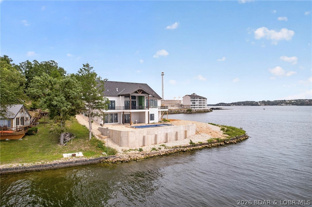 Brand new lakefront point estate showcasing breathtaking panoramic views from 2 combined lots with 316 feet of gentle shoreline, at the 4 Mile Marker of Lake of the Ozarks.  Designed for luxury living and effortless entertaining, this exceptional residence offers an unparalleled waterfront lifestyle with high-end finishes and thoughtfully curated throughout.  The stunning lakeside pool overlooks expansive main channel views, creating a private resort-style setting.  Inside, guests will enjoy a media/theater room, spacious game room, custom wet bar, private swimming pool just one step off the lower deck and multiple gathering spaces designed for memorable entertaining.  Sophisticated architecture, premium craftsmanship and extraordinary lake views combine to create a one-of-a-kind retreat that rivals a five-star resort.  Whether hosting family and friends, or enjoying a private lakeside escape, this remarkable new construction home delivers the ultimate luxury in waterfront living.  Perfect set up for huge custom designed dock with a protected breakwater system.