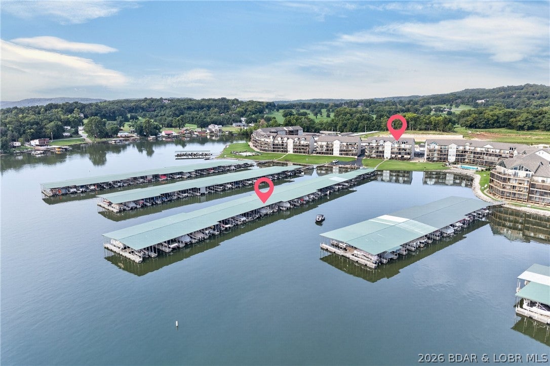 Welcome to Cedar Glen, where this top-floor loft condo delivers a killer view, over 1,400 square feet, and a location that is tough to beat! Vaulted ceilings and expansive lake views create an open, airy feel, while the main level offers a lakeside primary suite with deck access, guest bedroom, full guest bath, updated kitchen with granite countertops, and an open living/dining area anchored by a gas fireplace. Upstairs, the spacious bonus loft provides a second living area and flexibility for a possible third bedroom—perfect for family and guests. Offered fully furnished, the condo also features fresh paint, LVP flooring, updated glass shower doors, and newer refrigerator, microwave, washer, and dishwasher. A 10x24 boat slip on Dock 3 directly in front of the unit is included. Cedar Glen boasts super-flat lake frontage at the Big Niangua 13MM, two heated pools, boat ramp, trailer parking, sand volleyball, horseshoes, and a playground. Just 5 minutes from Camdenton and close to Ha Ha Tonka State Park, Lake Valley Golf, and Old Kinderhook!