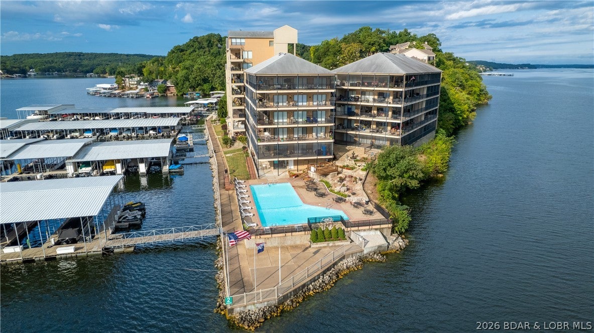 Lake life is easy at The Falls! This furnished 2-bedroom, 2-bath waterfront condo pairs wide lake views with the extras buyers want most: a 10x28 boat slip, 2 PWC spaces with lifts and an assigned covered parking space. An elevator right at the front door makes coming and going with groceries, luggage and Lake gear a breeze. Inside, the 1,180 sq ft single-level floor plan feels open and comfortable, with an updated kitchen, spacious living area, fireplace and wet bar. Step onto the large screened, covered deck and take in the cove setting and main channel views, perfect for morning coffee, sunset drinks or relaxing after a day on the water. The primary bedroom offers direct deck access and a lake view. The Falls offers community pools, clubhouse and tennis courts, plus nightly rentals are allowed for income potential. Offered furnished and ready to enjoy, this is a complete Lake of the Ozarks package.