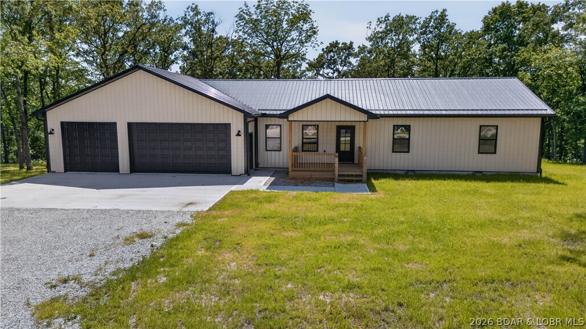 Beautiful, newly constructed home situated on approximately 6.5± acres just minutes from Warsaw and Truman Lake access. This3-bed, 2-bath home features durable metal siding, a metal roof, and a large, covered deck, the perfect place to relax and enjoy peaceful evenings overlooking your acreage. Inside, you'll find a spacious living room along with a well-designed kitchen showcasing beautiful wood cabinetry, abundant counter space, and a convenient walk-in pantry. The primary suite offers a comfortable retreat with a private ensuite bathroom and a large walk-in closet. Two additional bedrooms are generously sized and provide plenty of space for family or visitors. The property also includes a large 3-car attached shop, offering excellent space for your boat, vehicles, and recreational equipment—ideal for anyone looking to enjoy everything Truman Lake living has to offer.