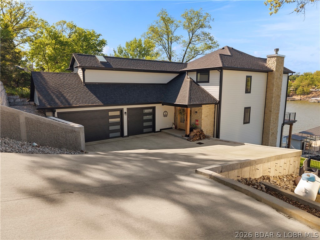 Custom-built in 2024 and perfectly positioned at the 17MM in the heart of Osage Beach, this move-in ready lakefront retreat delivers luxury, comfort, and effortless entertaining. Soaring ceilings and an open-concept layout create a grand yet inviting feel, anchored by two fireplaces, including a dramatic floor-to-ceiling stone fireplace. The high-end kitchen features premium appliances and custom cabinetry throughout, from the built-ins to the impressive primary closet. The third floor is a private primary suite with a hidden office, custom closet, spa-inspired bath with heated floors, custom shower, and oversized soaking tub. The lower level offers a mother-in-law suite, hidden room, and storm shelter/storage beneath the concrete patio. Outside, the dream dock is built for true lake living with a massive 2-well setup, PWC lift, covered and uncovered entertaining areas, swim platform, bar, deep water, and boosted Wi-Fi to the dock. A cart path from the oversized 3-car garage makes access easy. With James Hardie siding, low-maintenance landscaping, sprinkler system, 2 Sonos systems, no HOA, and proximity to The Reserve and Osage Beach attractions, this is lake luxury at its finest.